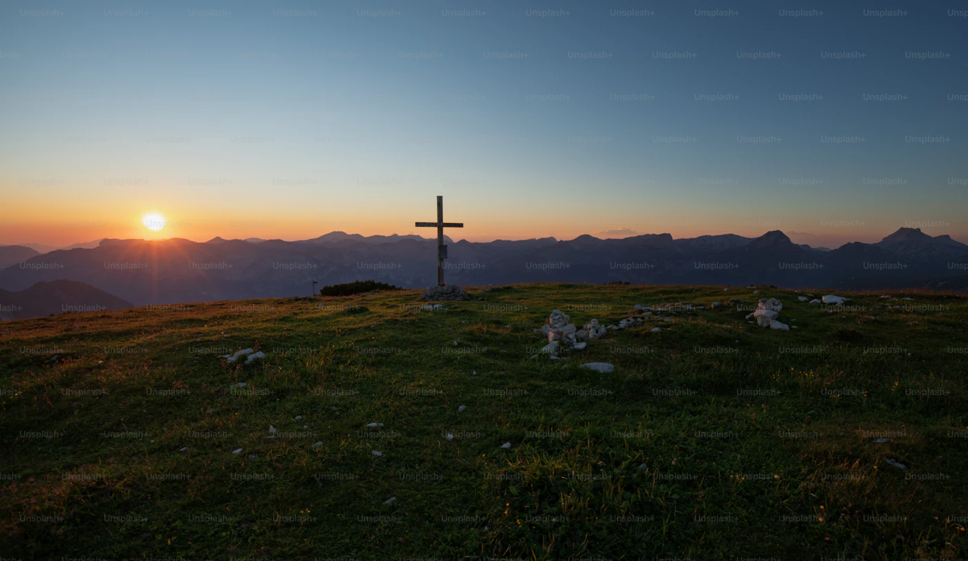 A wooden cross silhouetted against a sunset sky