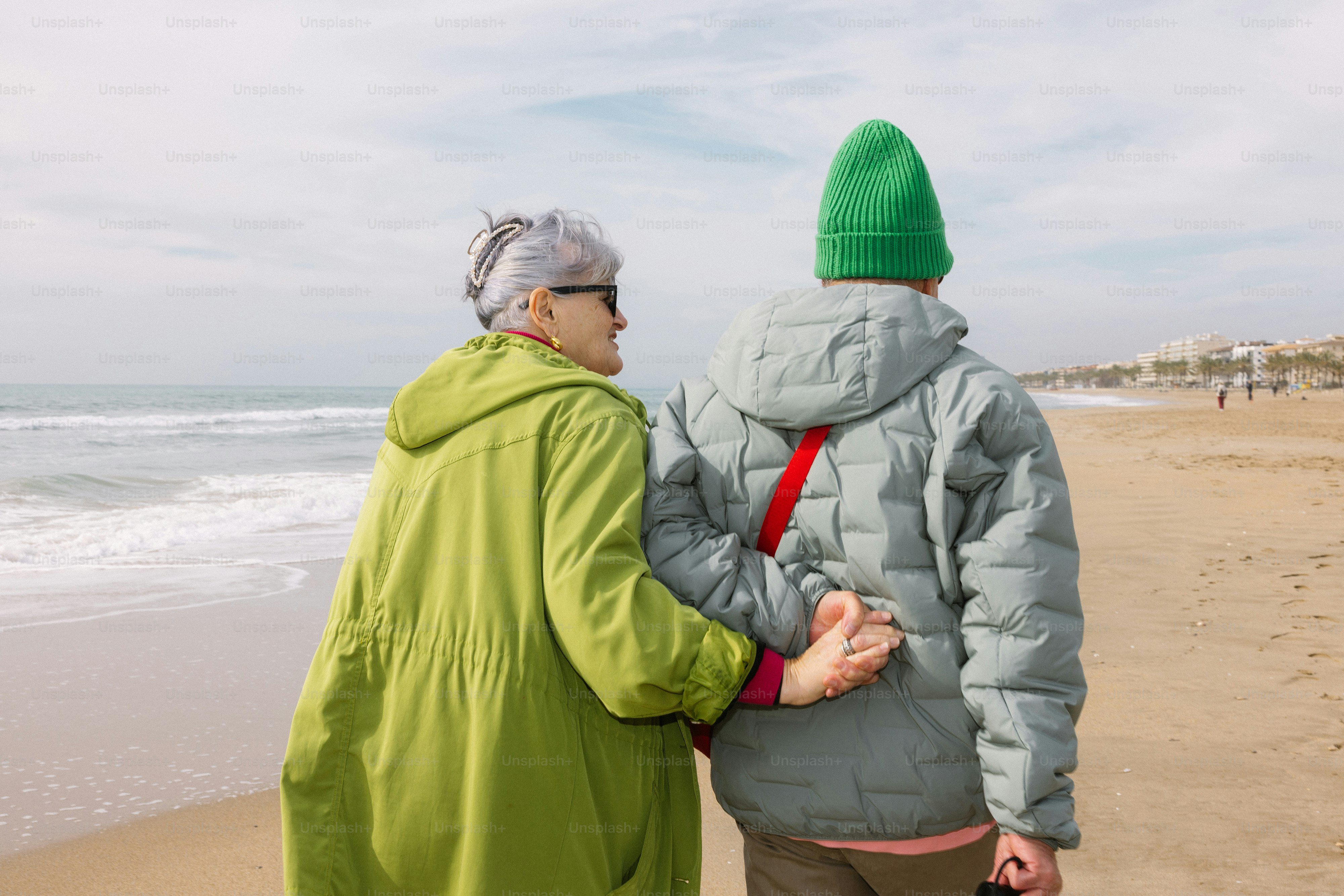 Duas pessoas caminhando numa praia perto do oceano.
