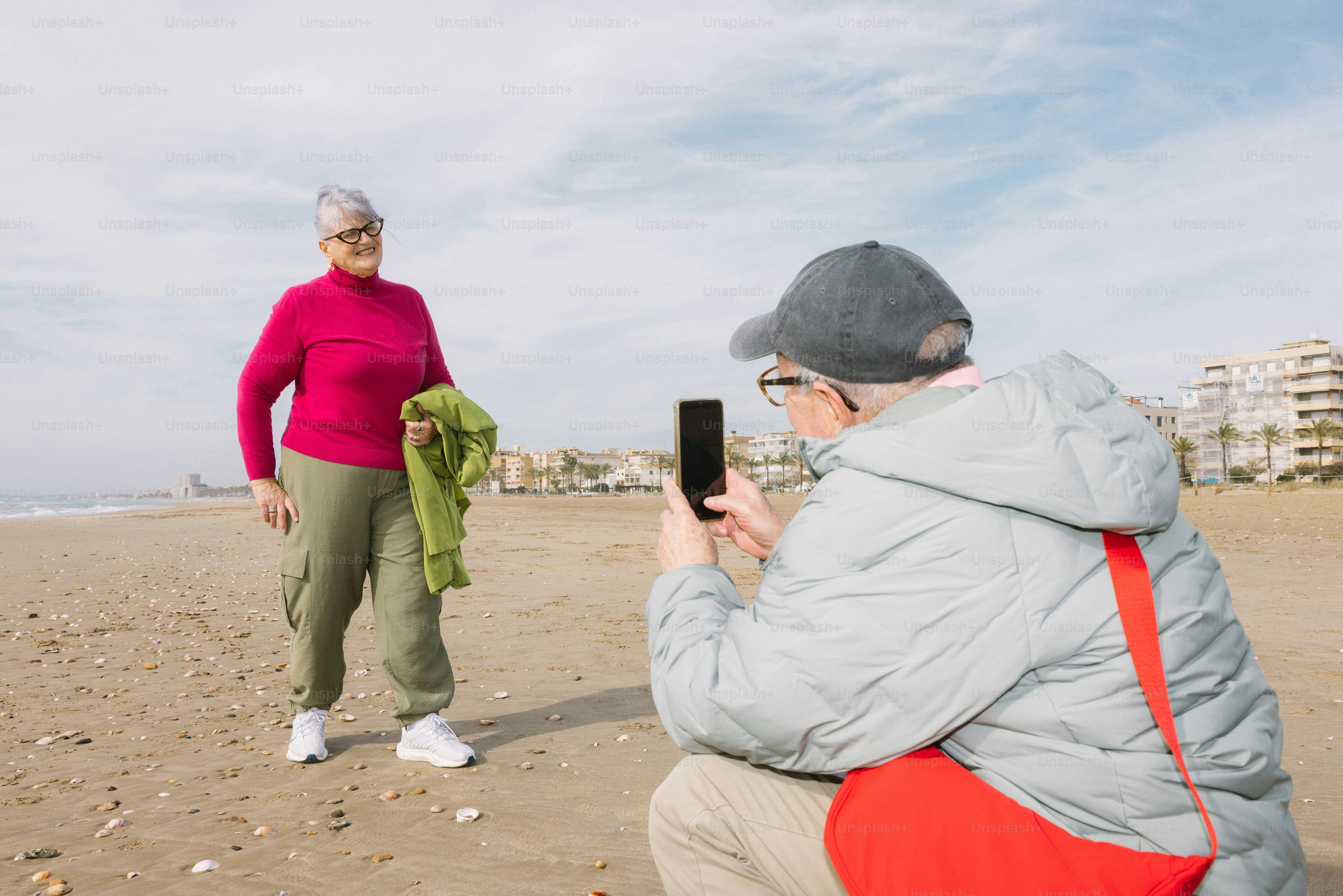 Casal idoso tirando uma foto na praia.