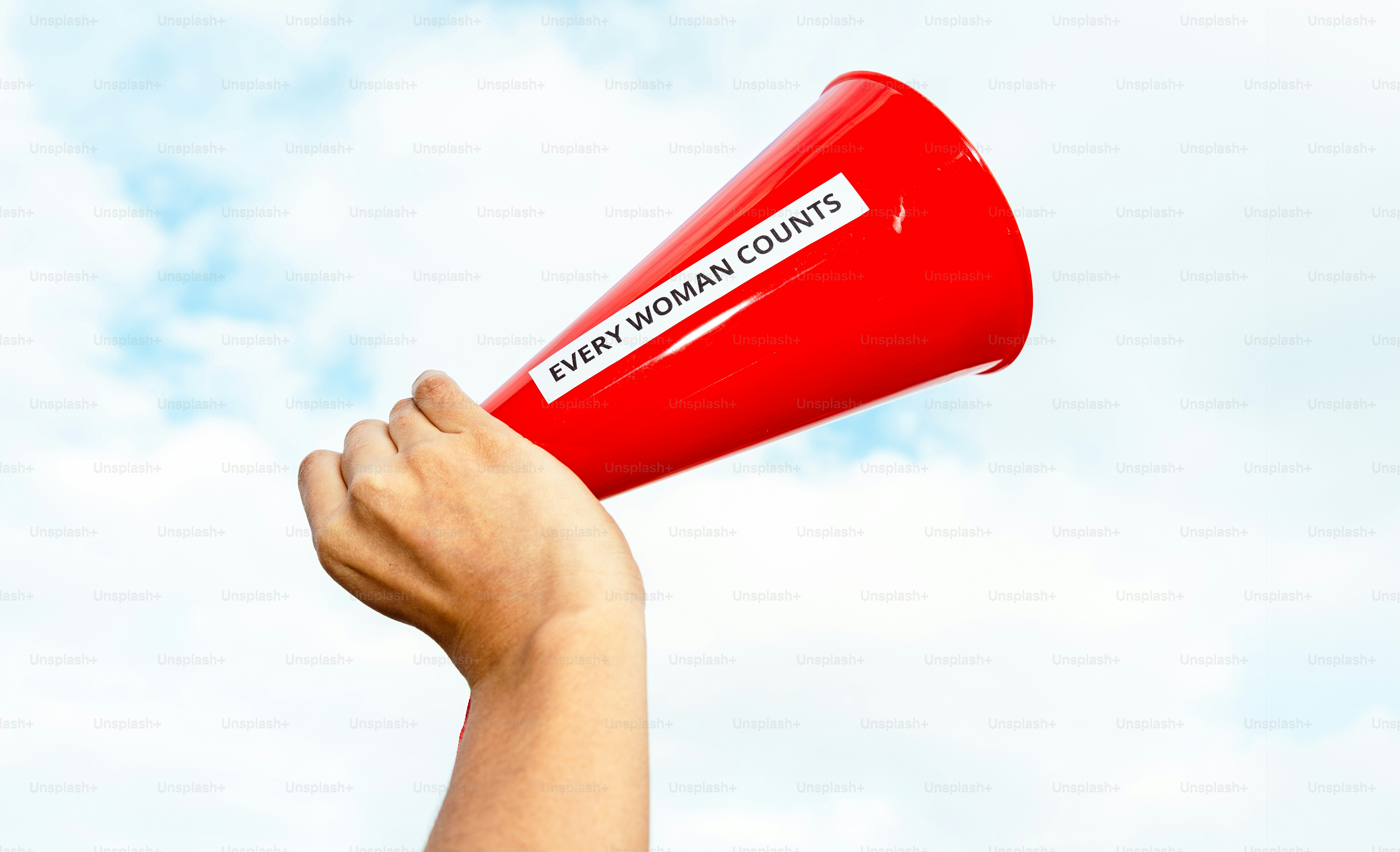 Die Hand hält ein rotes Megafon mit dem Text "Jede Frau zählt".