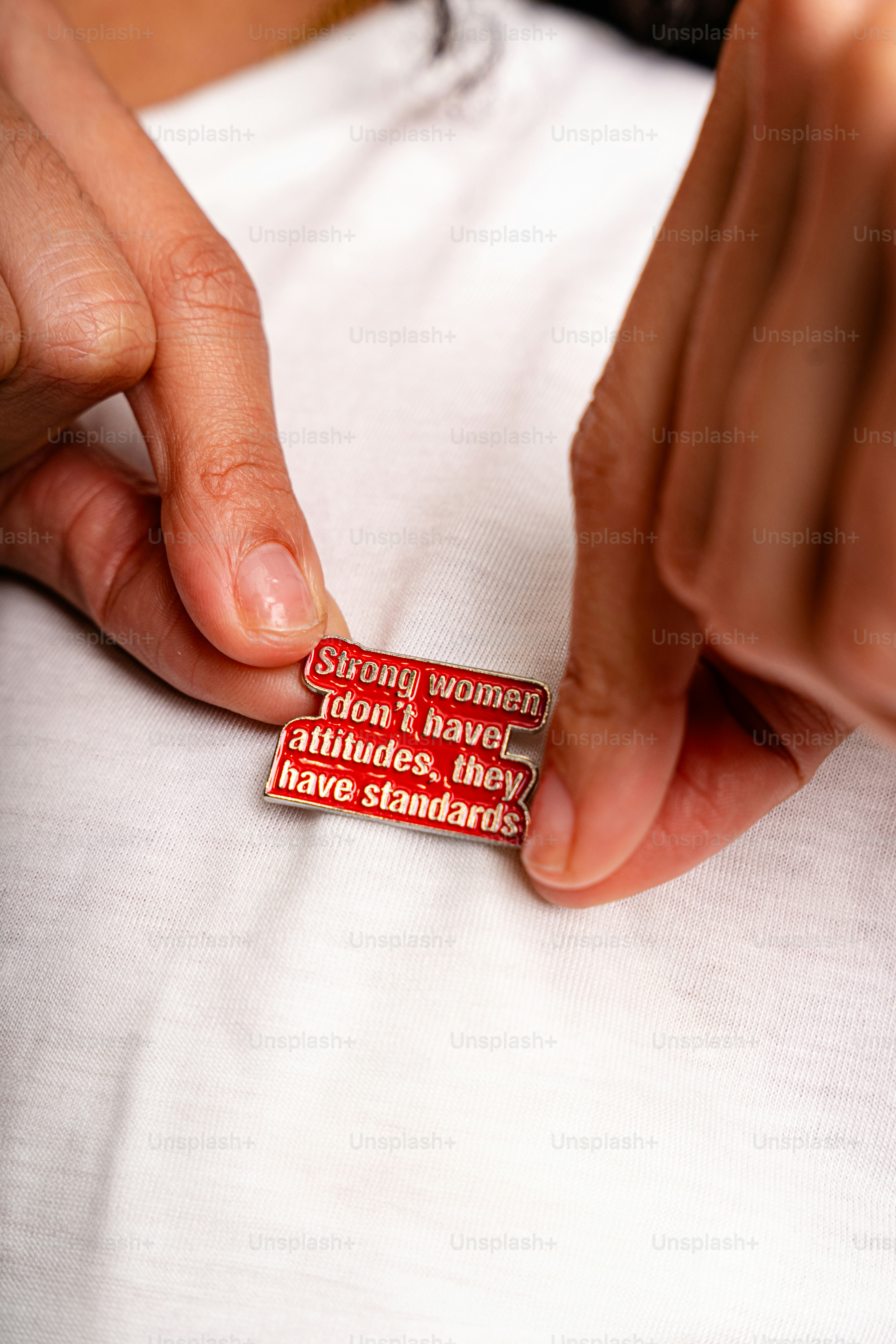 Manos sujetando un pin con una cita sobre estándares.