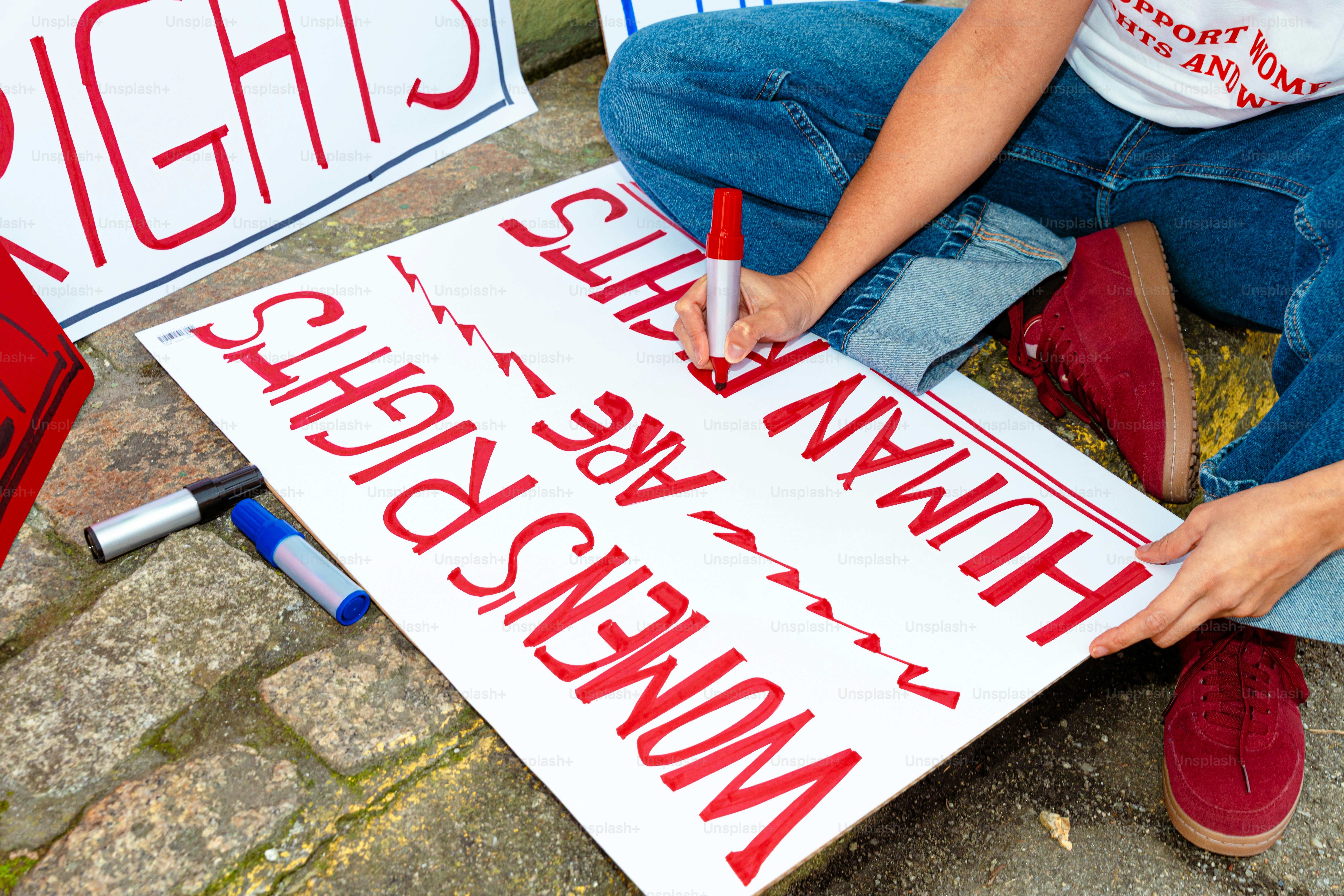 Person, die auf ein Schild schreibt "Frauenrechte sind Menschenrechte"