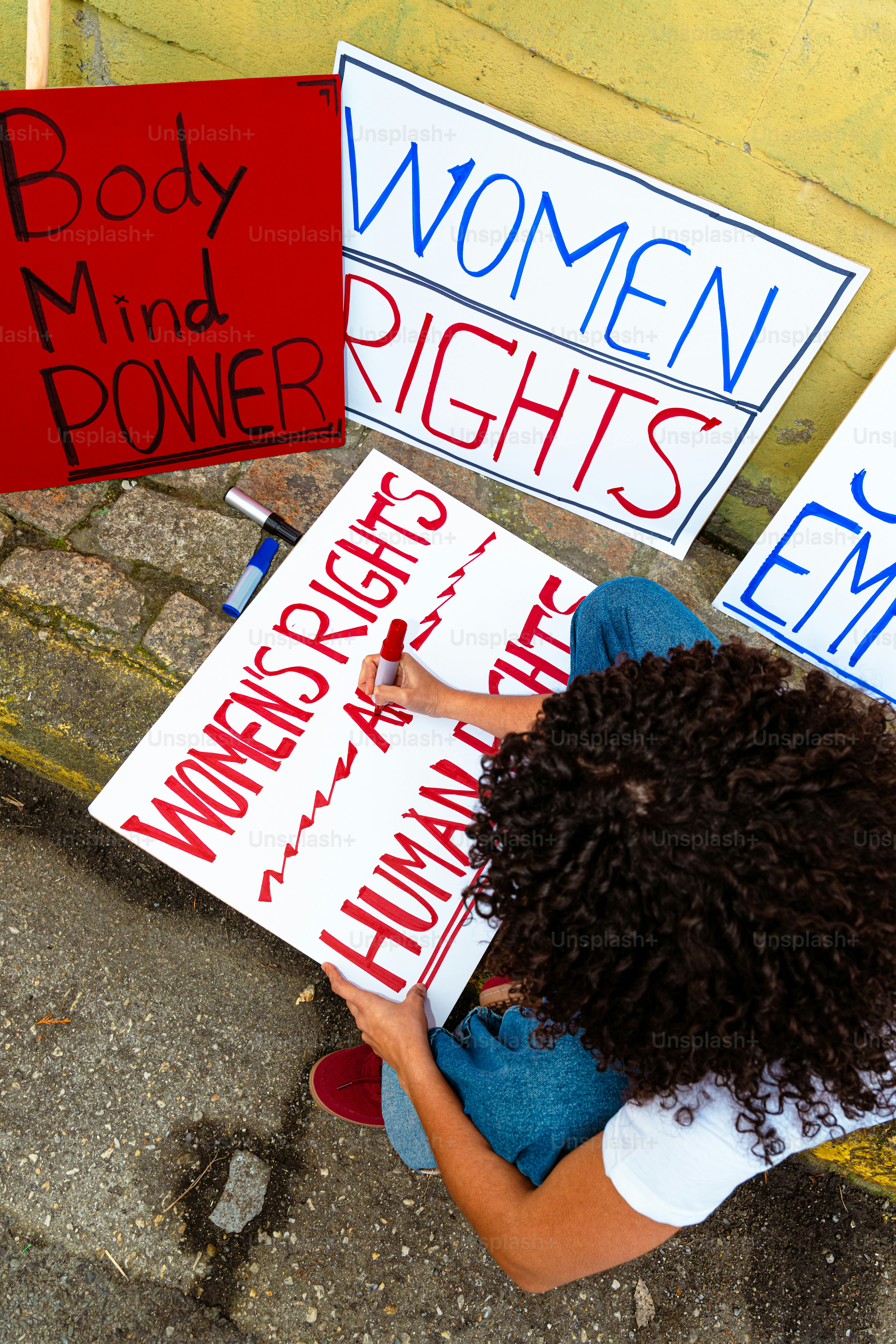 Woman writing "women's rights are human rights" on sign.
