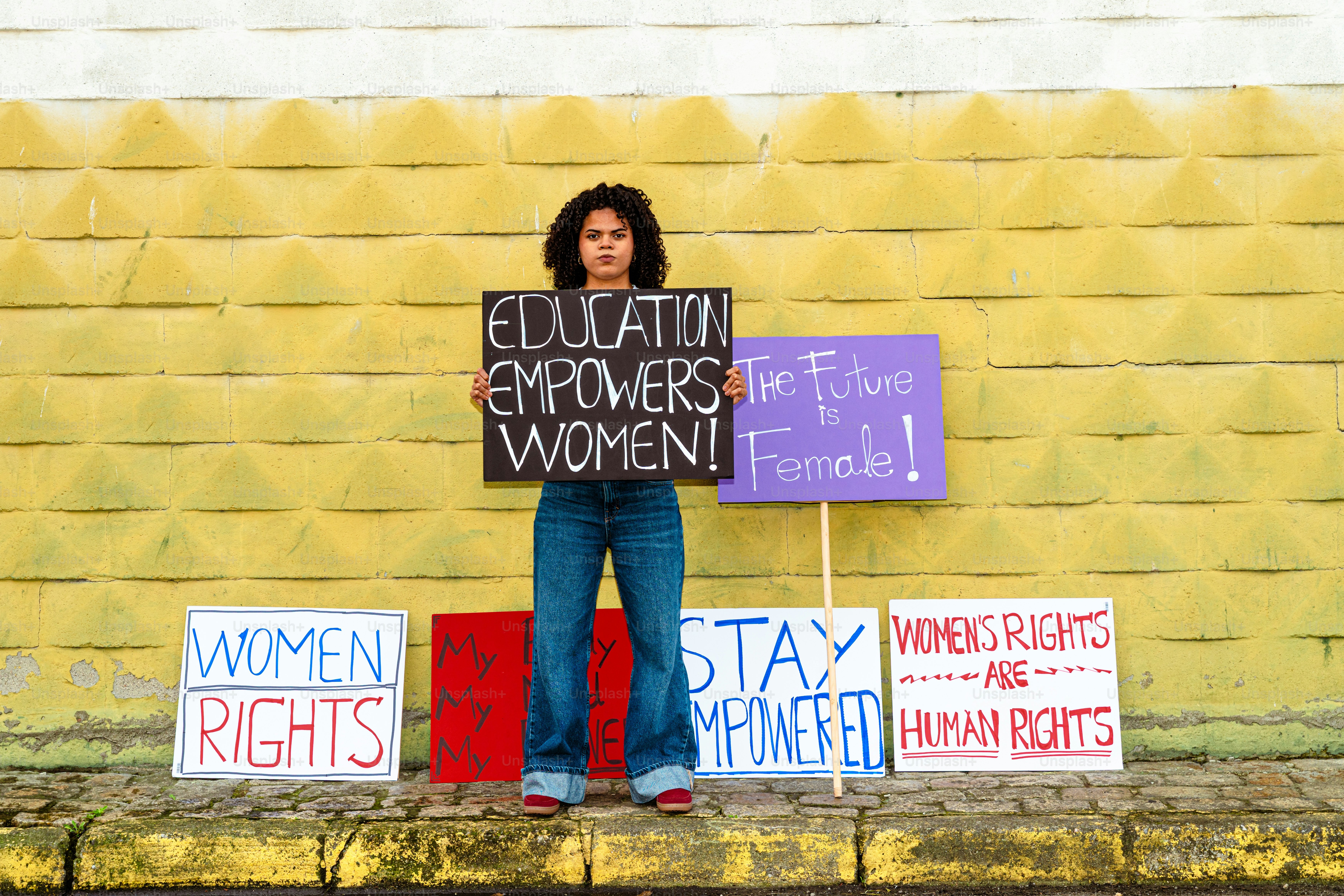 Woman holding signs advocating for women's rights and education.