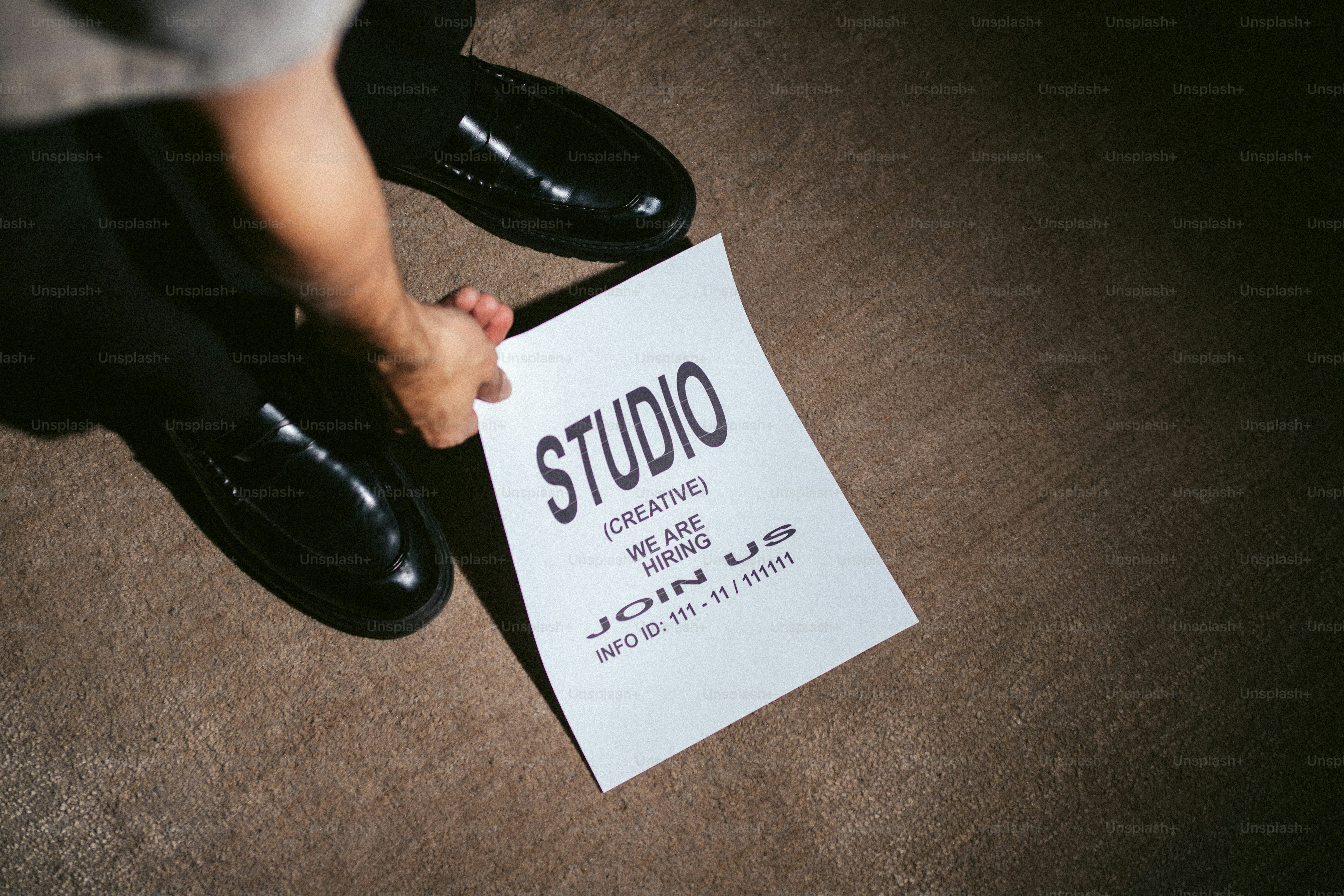 Tangan memegang selebaran perekrutan "studio" di lantai