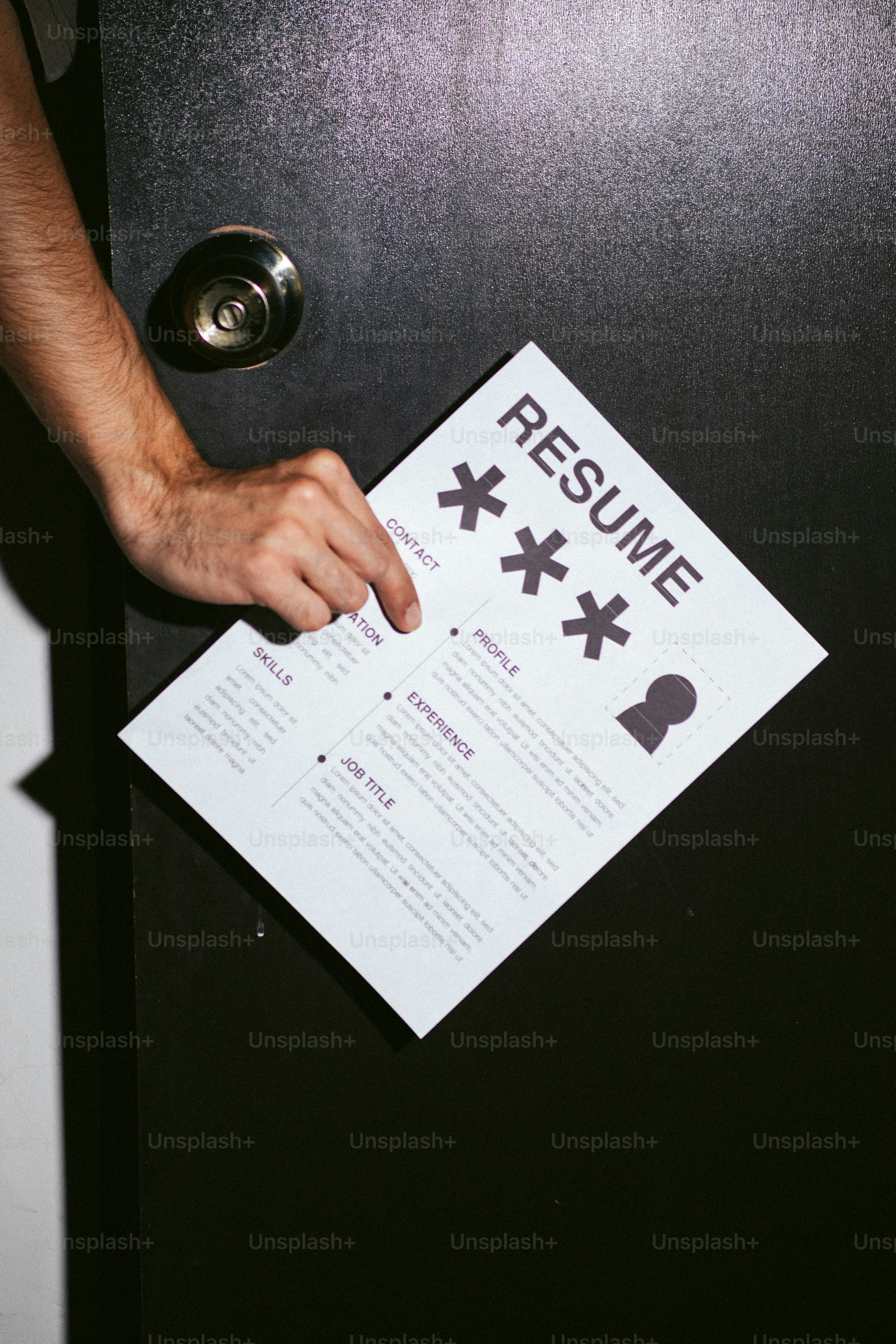 Hand holding a resume at a door