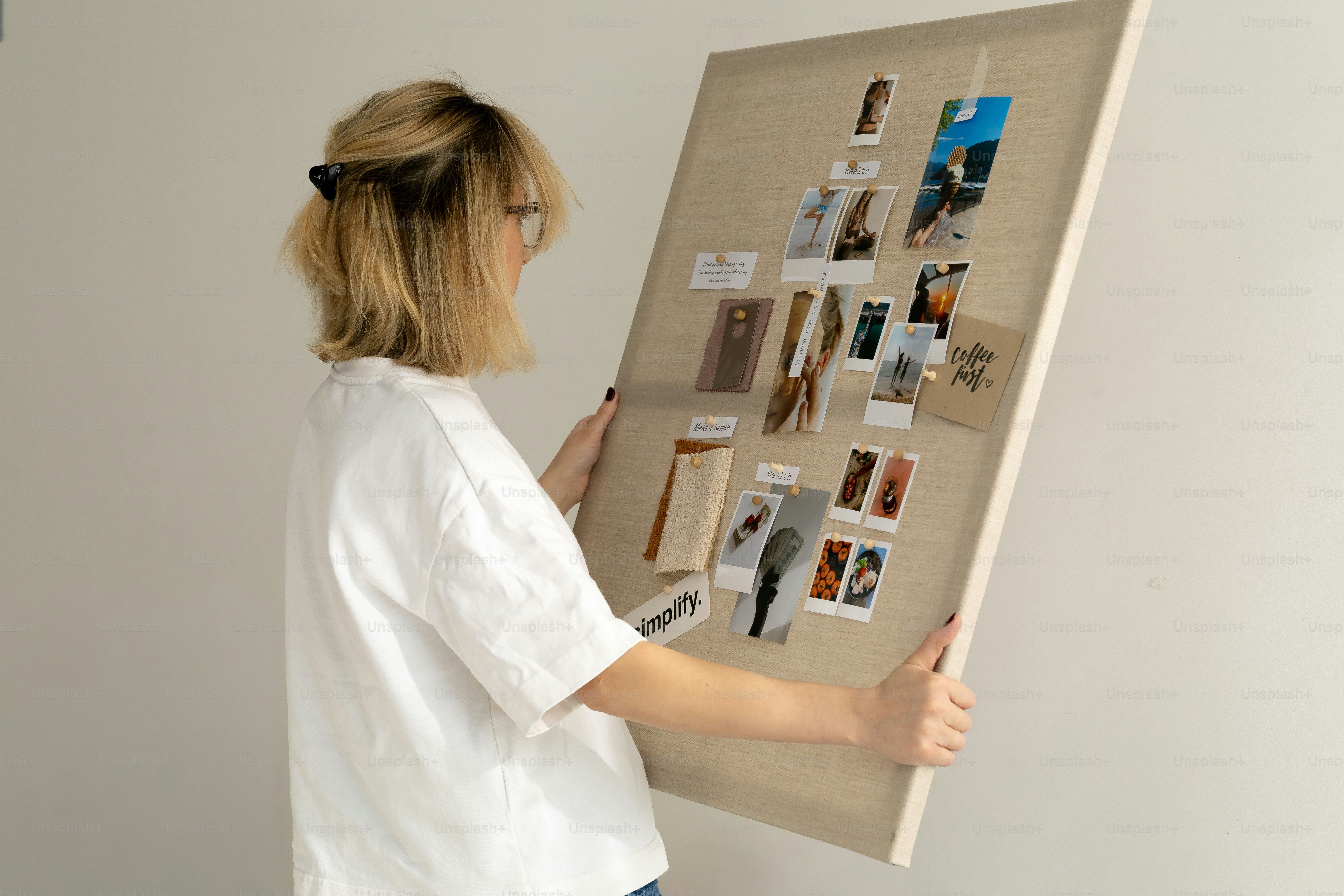 Woman arranging photos on a cork board.