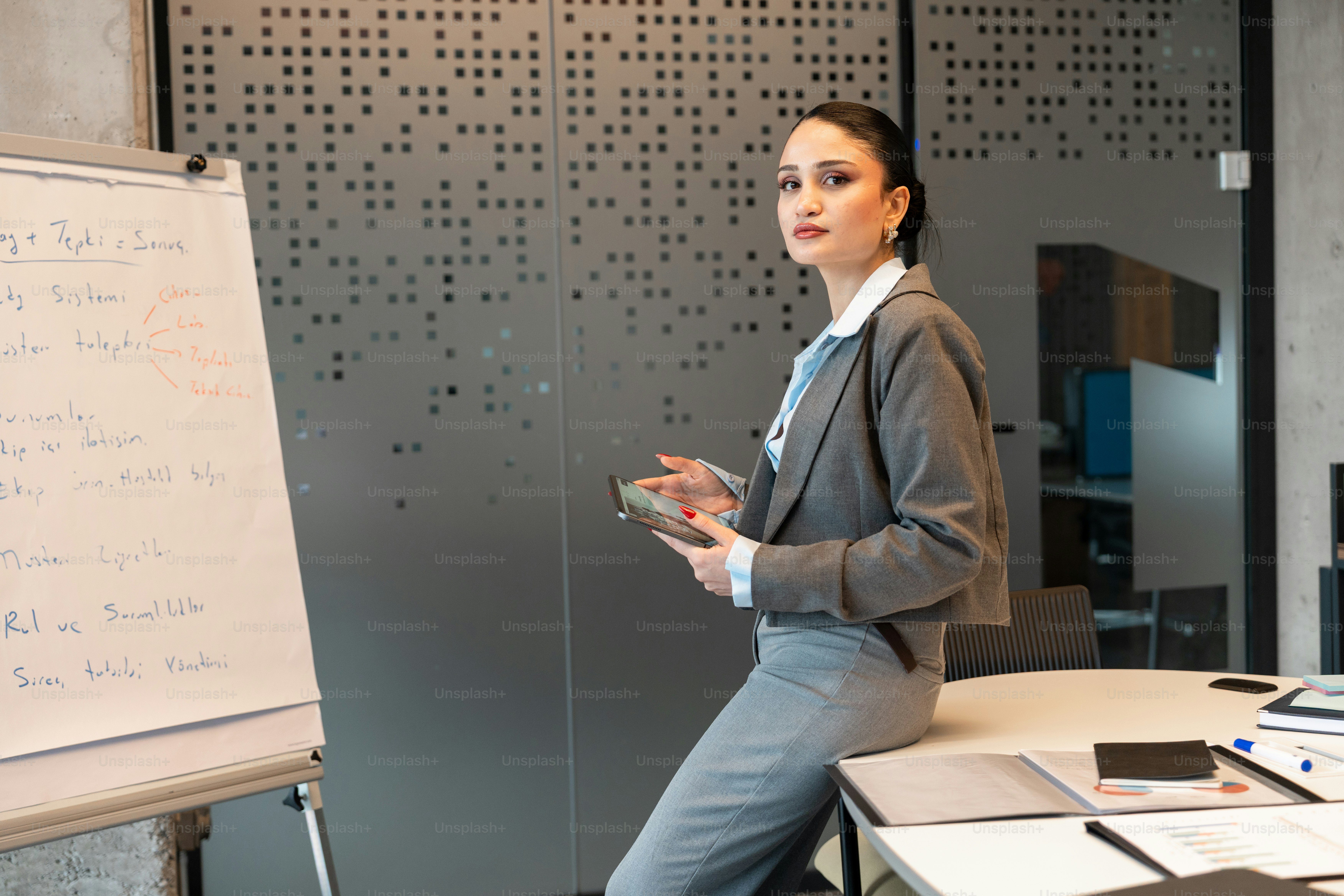 A woman in a suit presenting at a whiteboard. photo – Meeting Image on ...