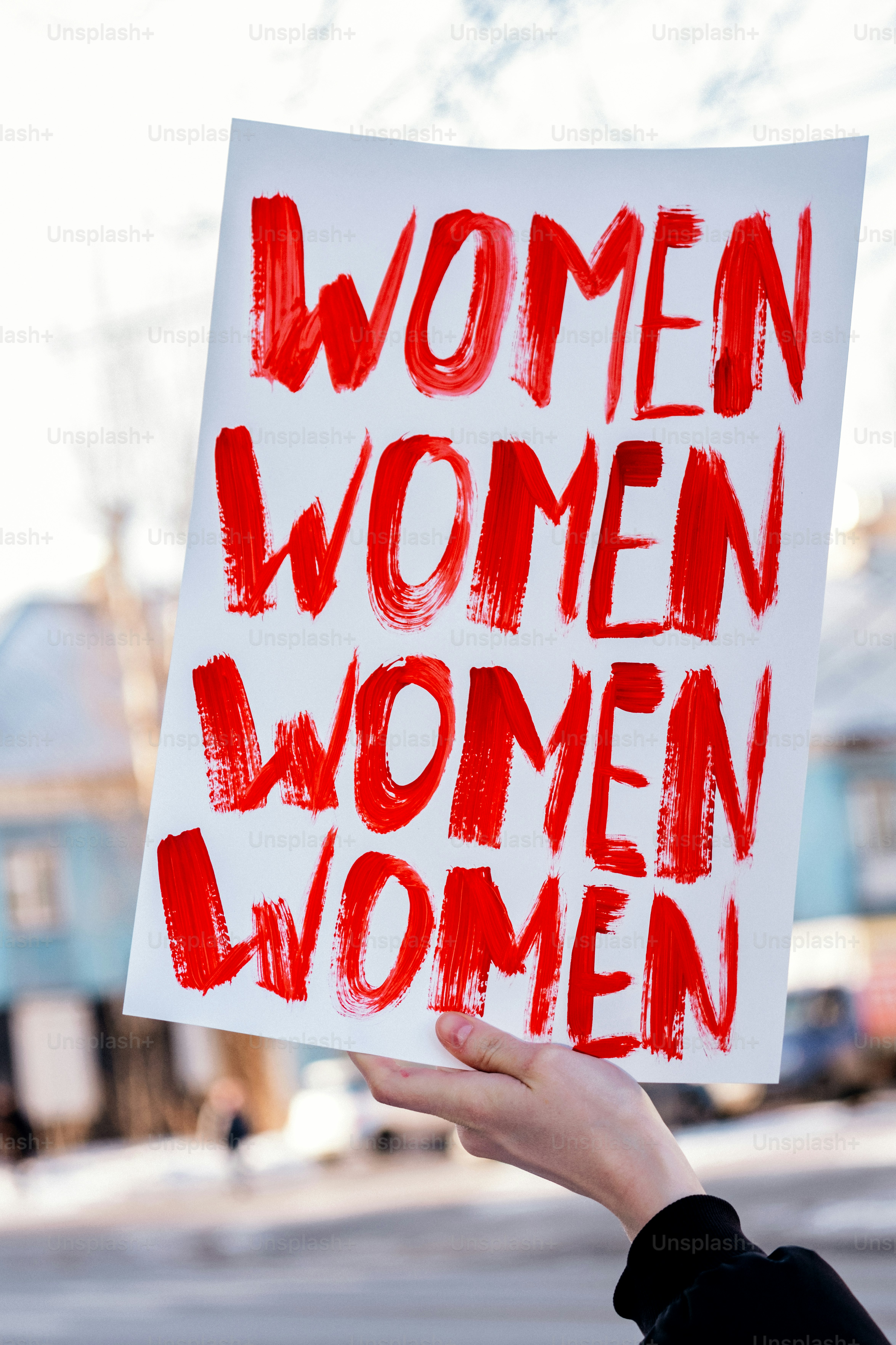 Un cartello con "donne" scritto quattro volte in rosso.