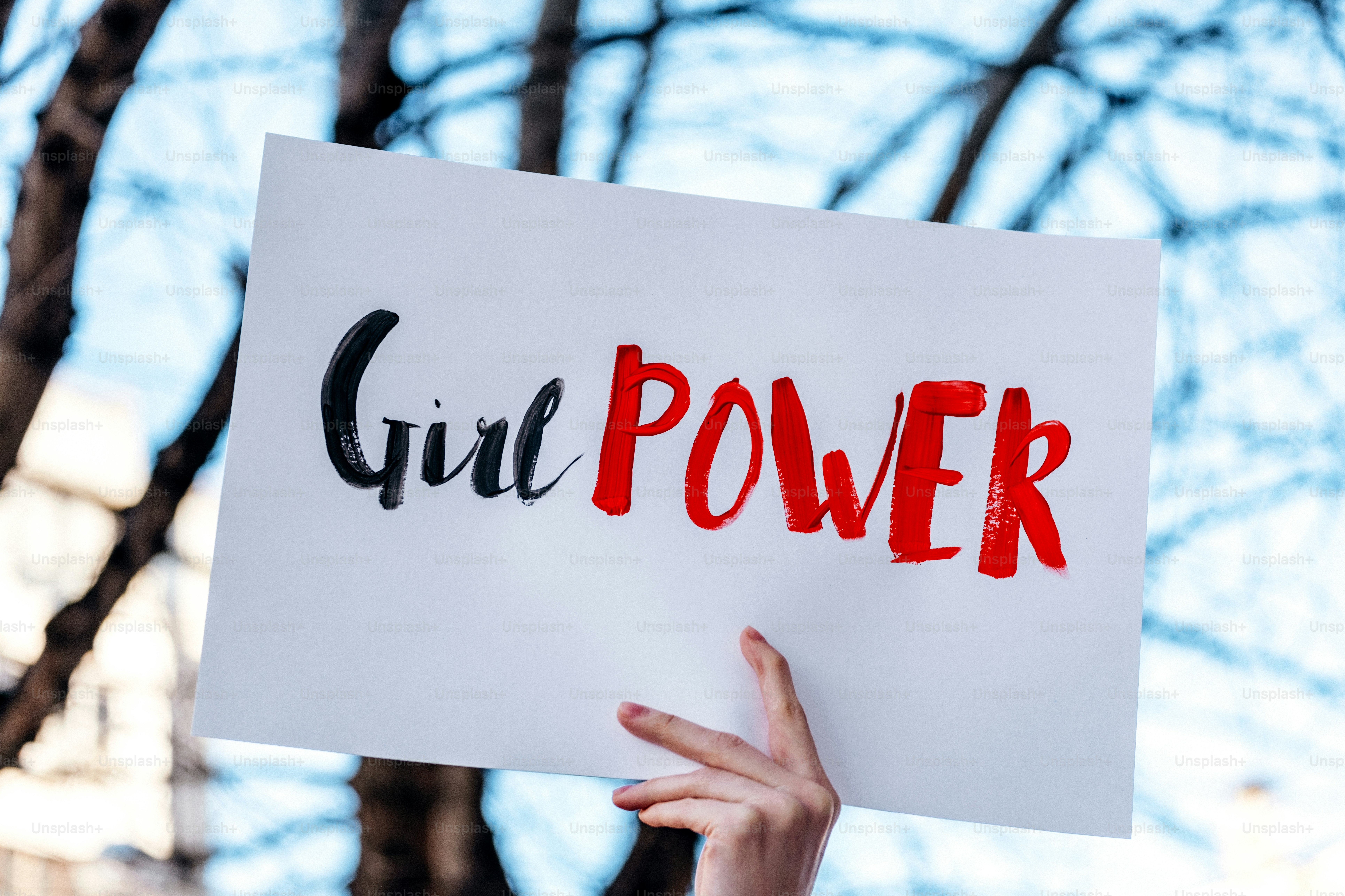 Une main tient un panneau sur lequel il est écrit « girl power »