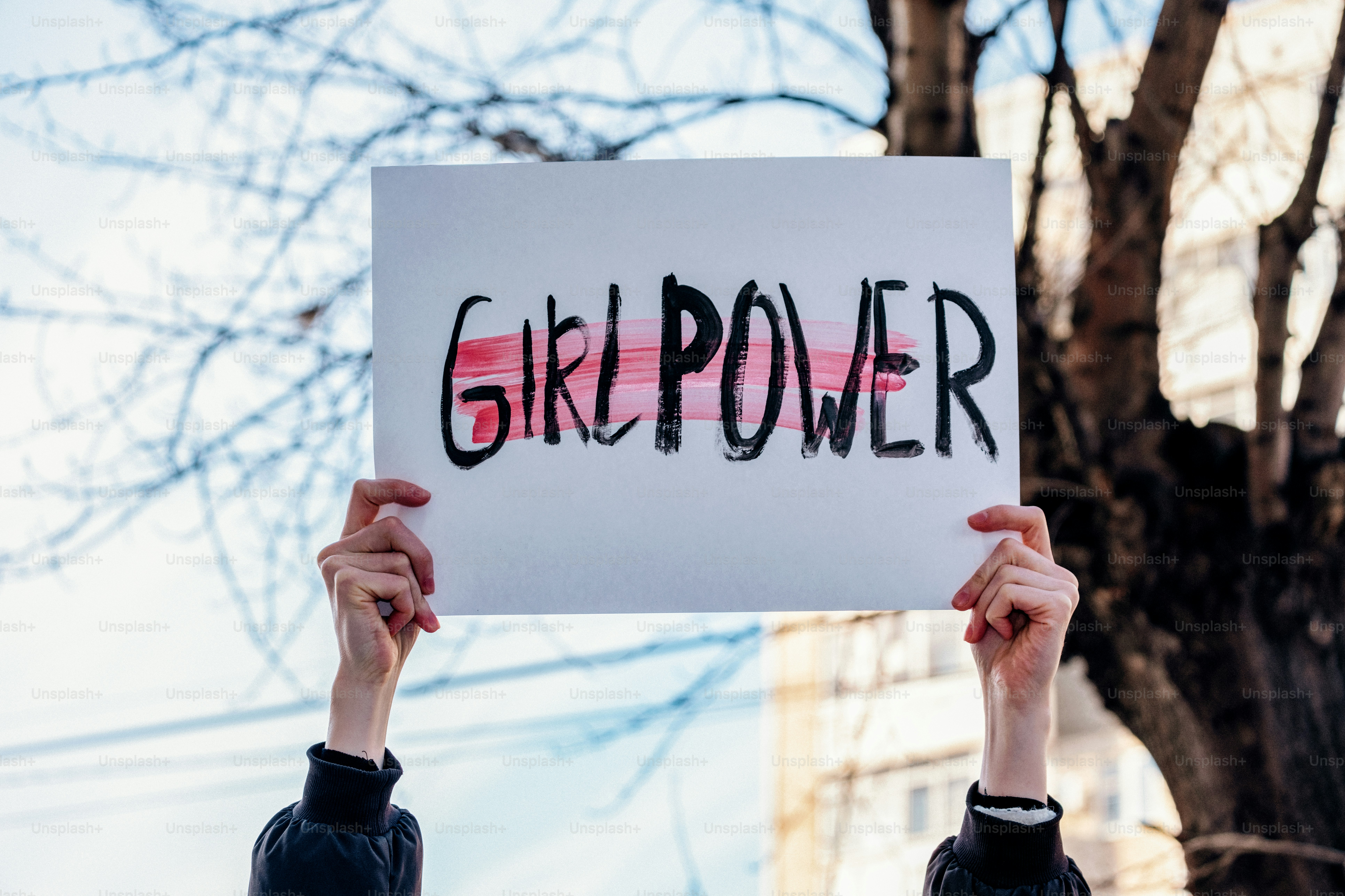 Les mains tiennent un panneau sur lequel il est écrit « girl power »