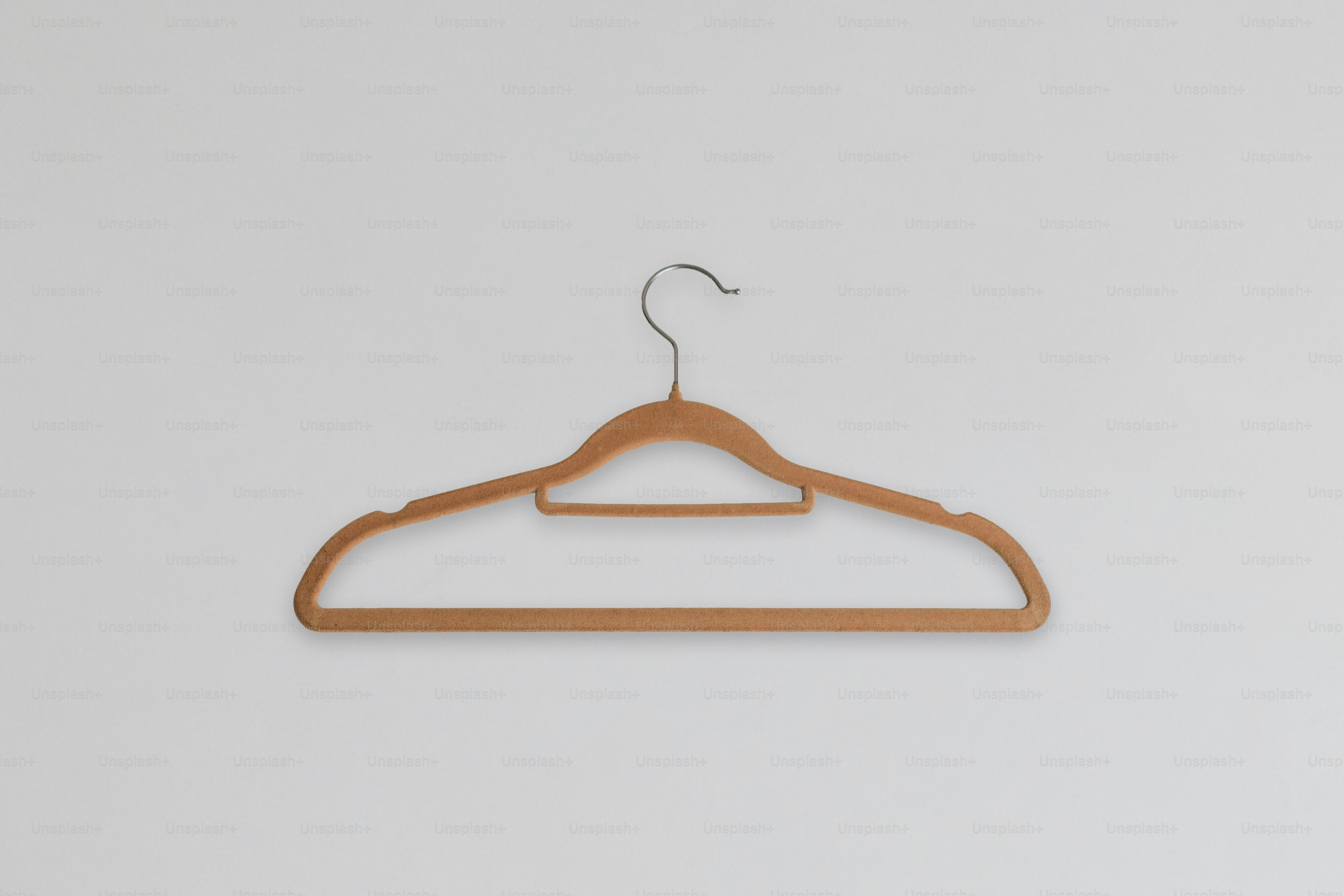 A single wooden hanger on a white wall.