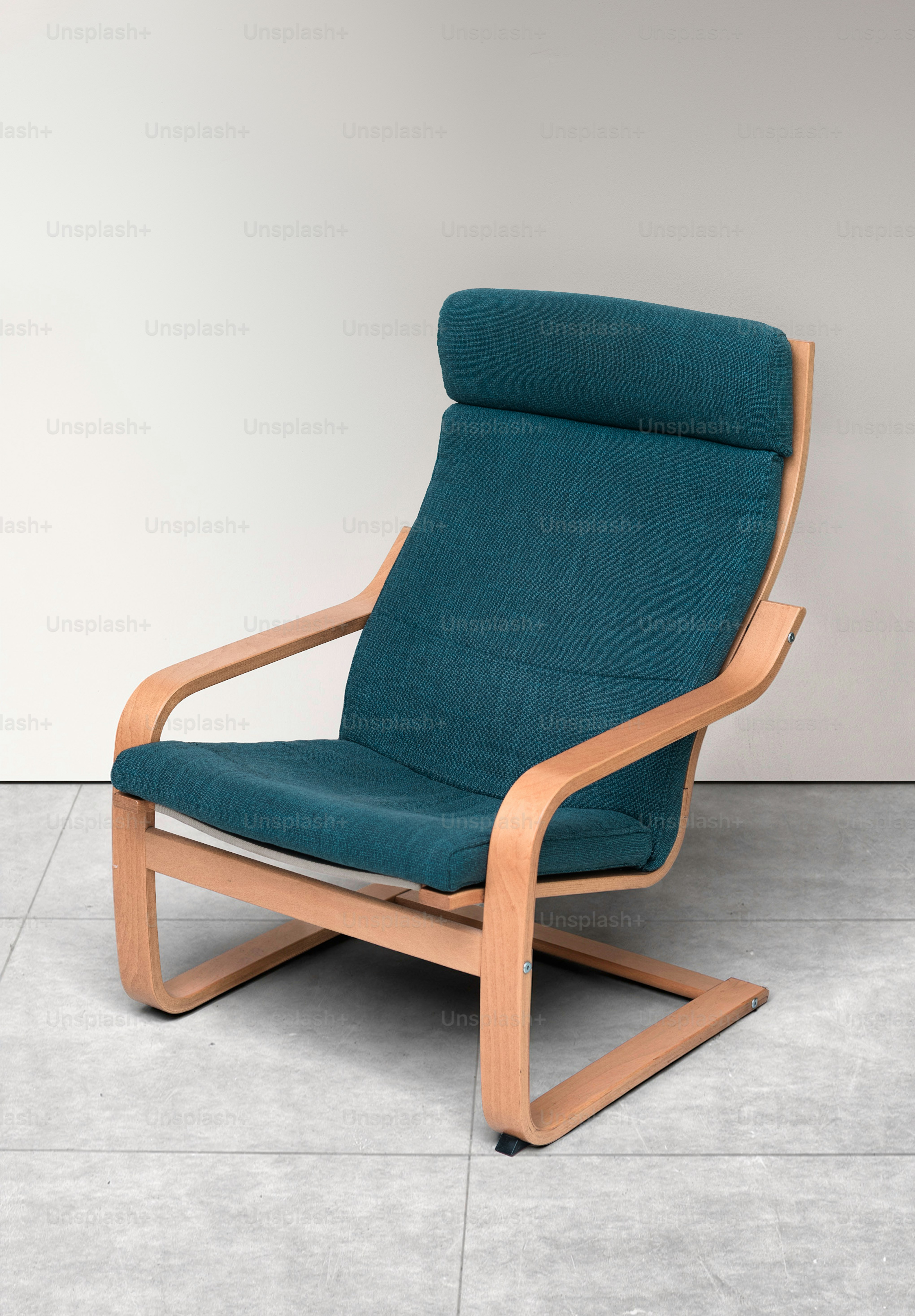 A modern armchair with teal upholstery and wooden frame