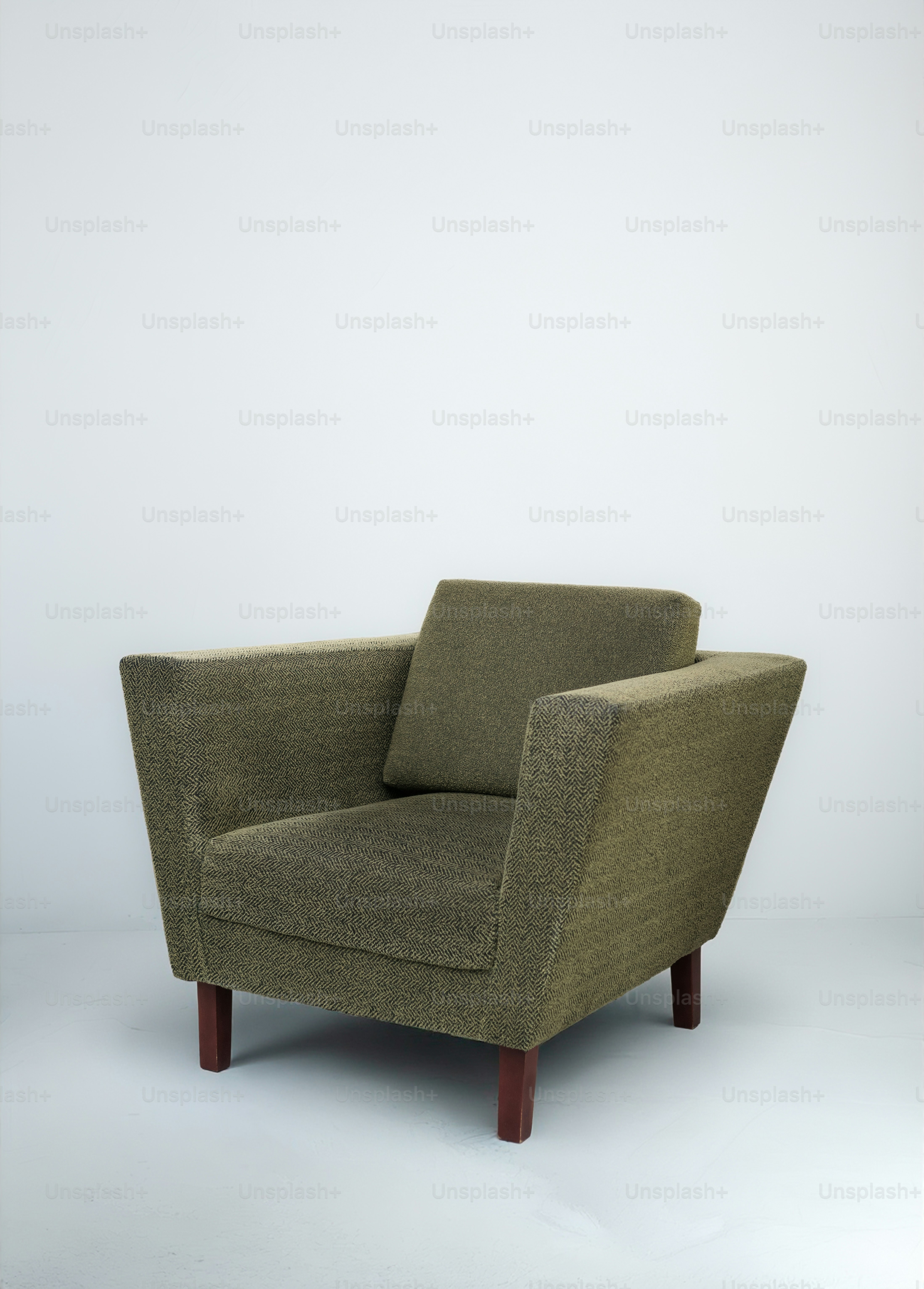 A modern green armchair with wooden legs