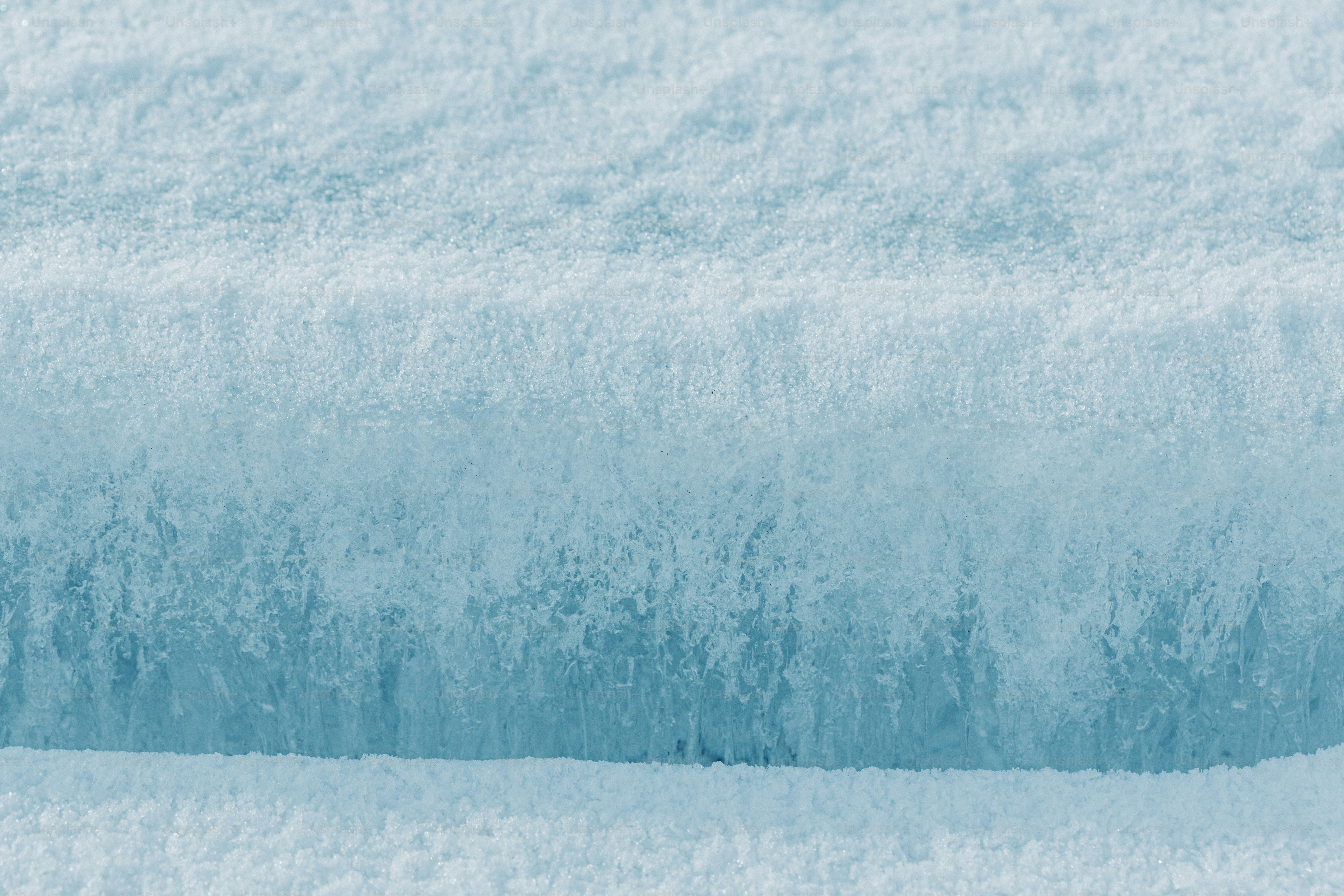 白い雪が広がるテクスチャーのある青い氷のクローズアップ