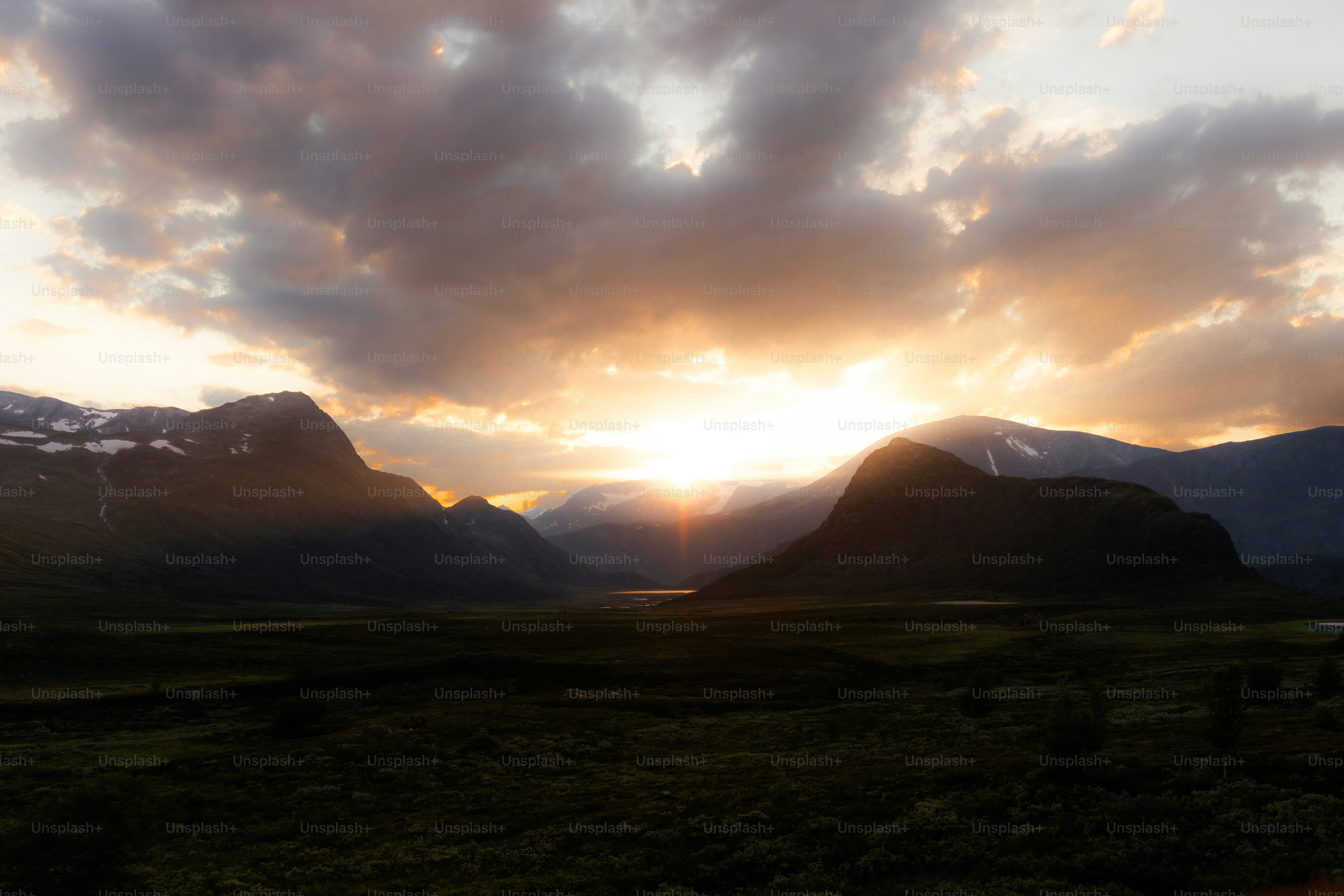 広大な山谷に夕焼けが広がり、劇的な雲が広がっています。