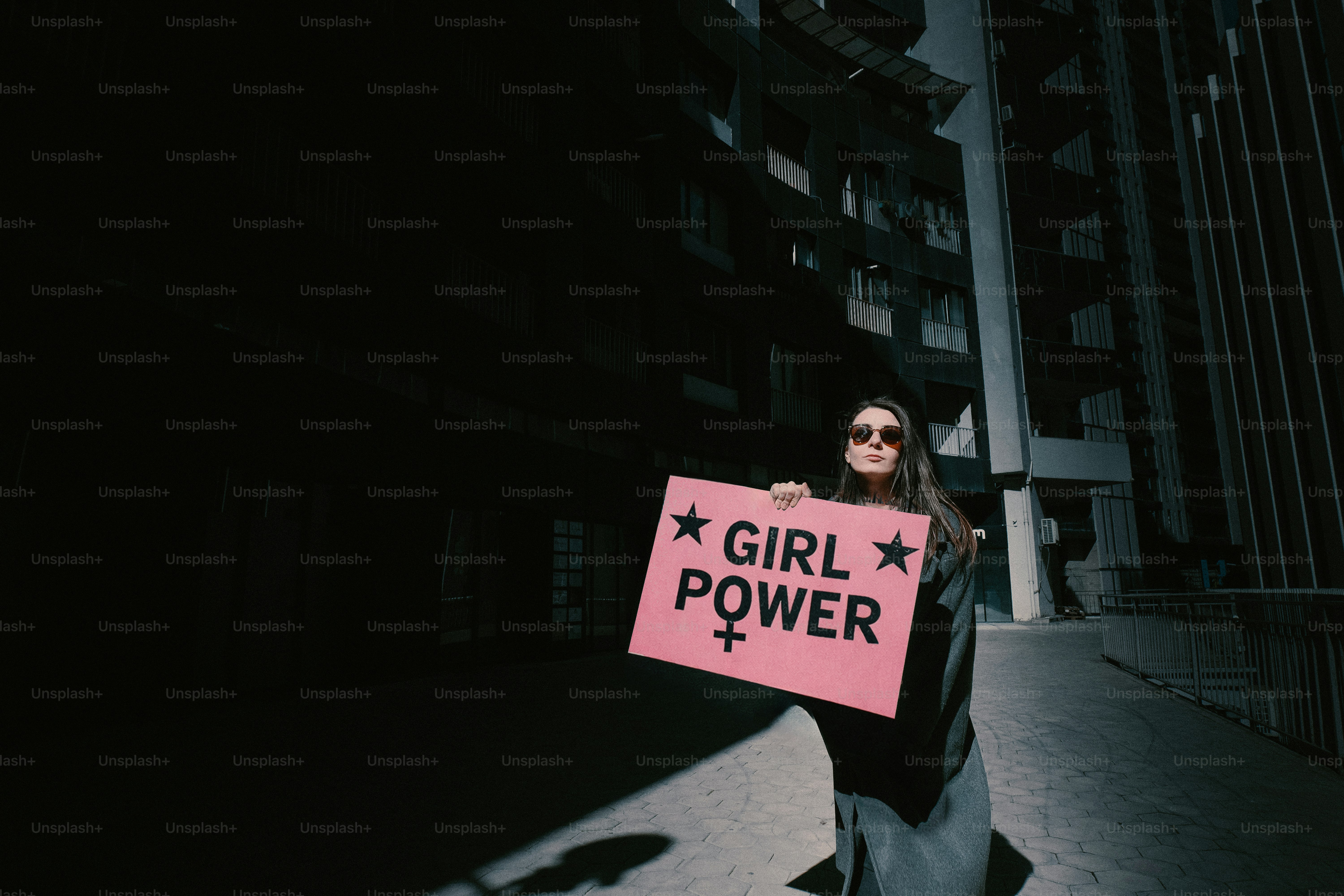 Woman holding a pink "girl power" sign outside.