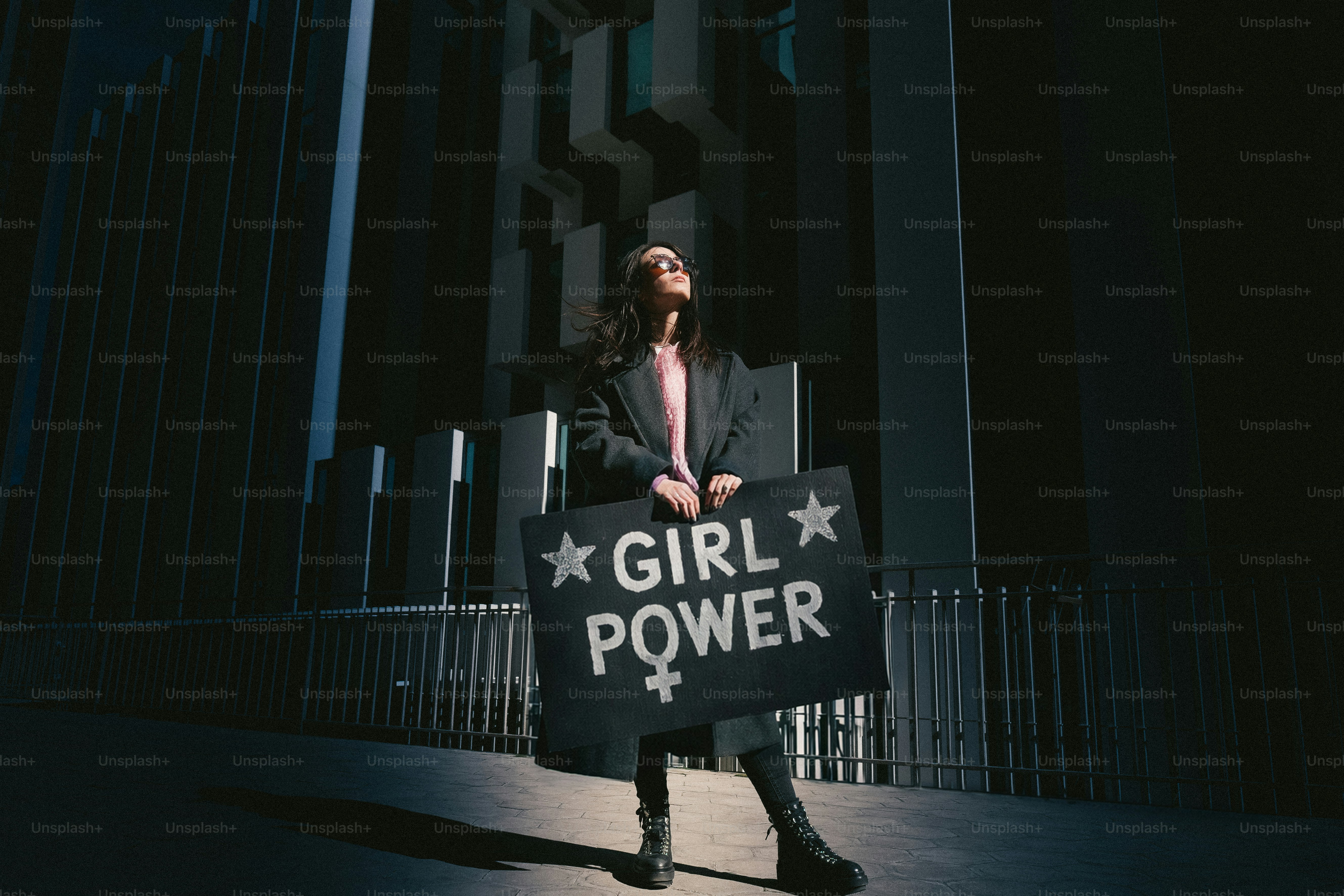Woman holds "girl power" sign with stars and venus symbol.