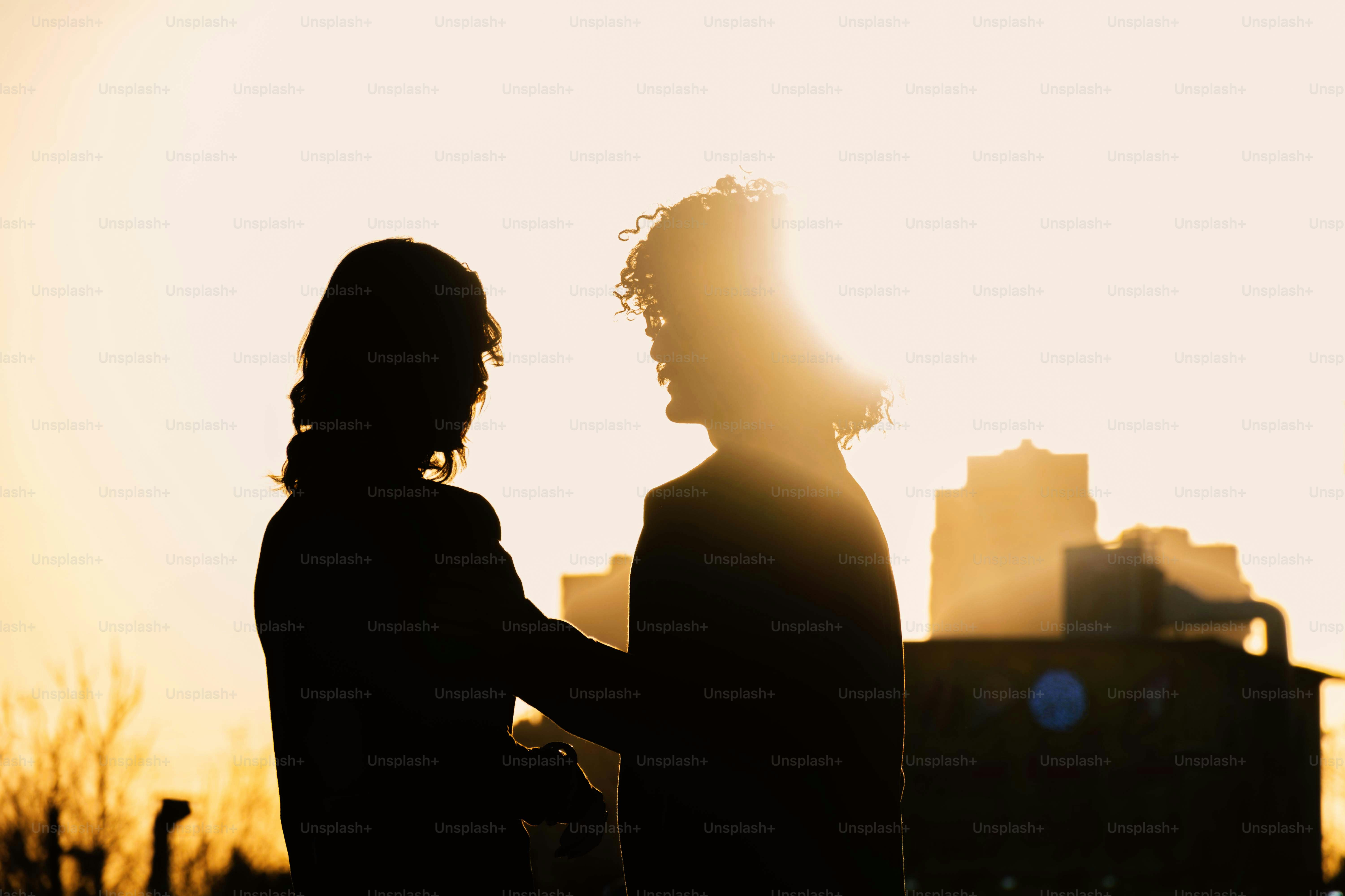 Dos personas recortadas contra una brillante puesta de sol