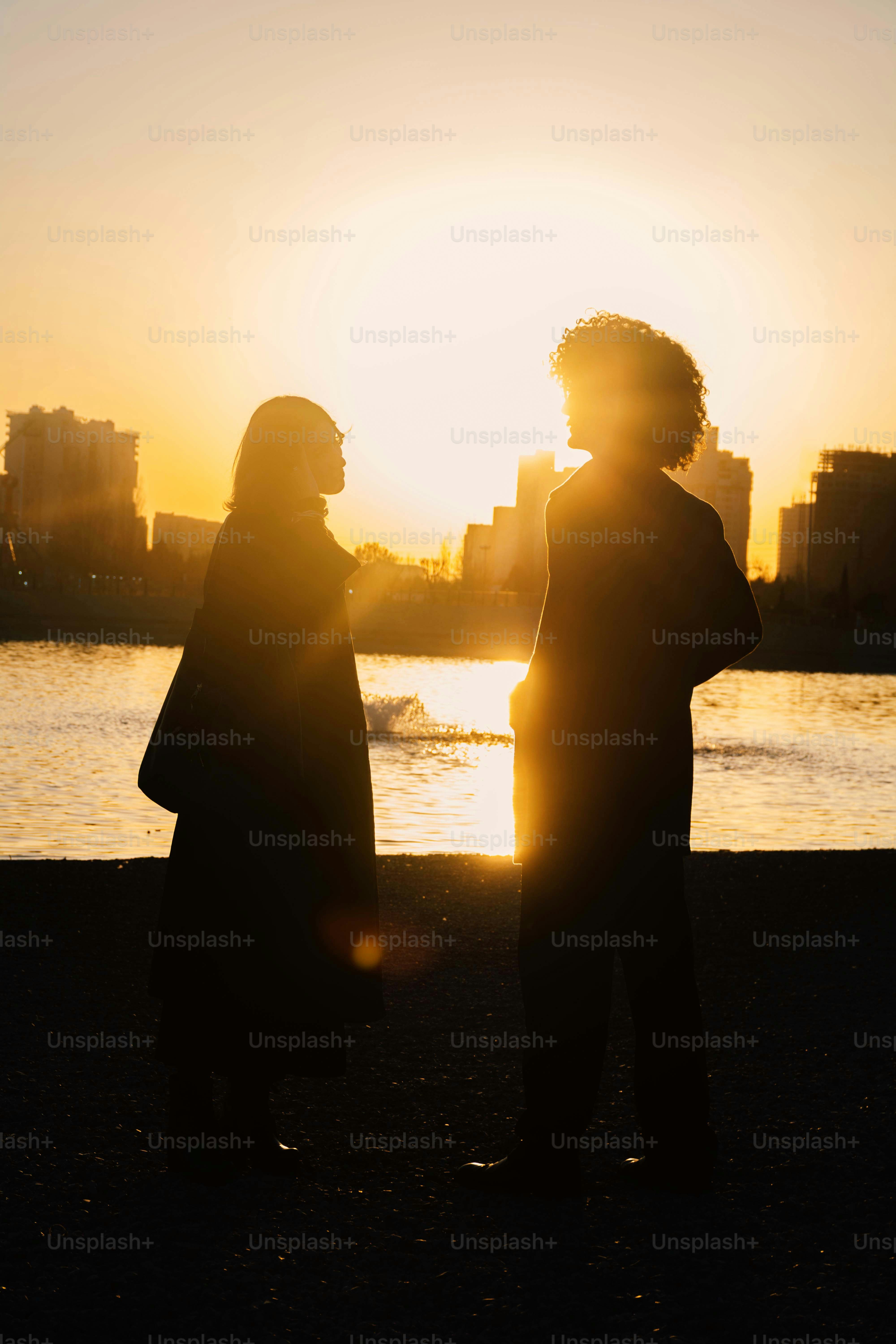 Dos personas recortadas contra un paisaje urbano al atardecer
