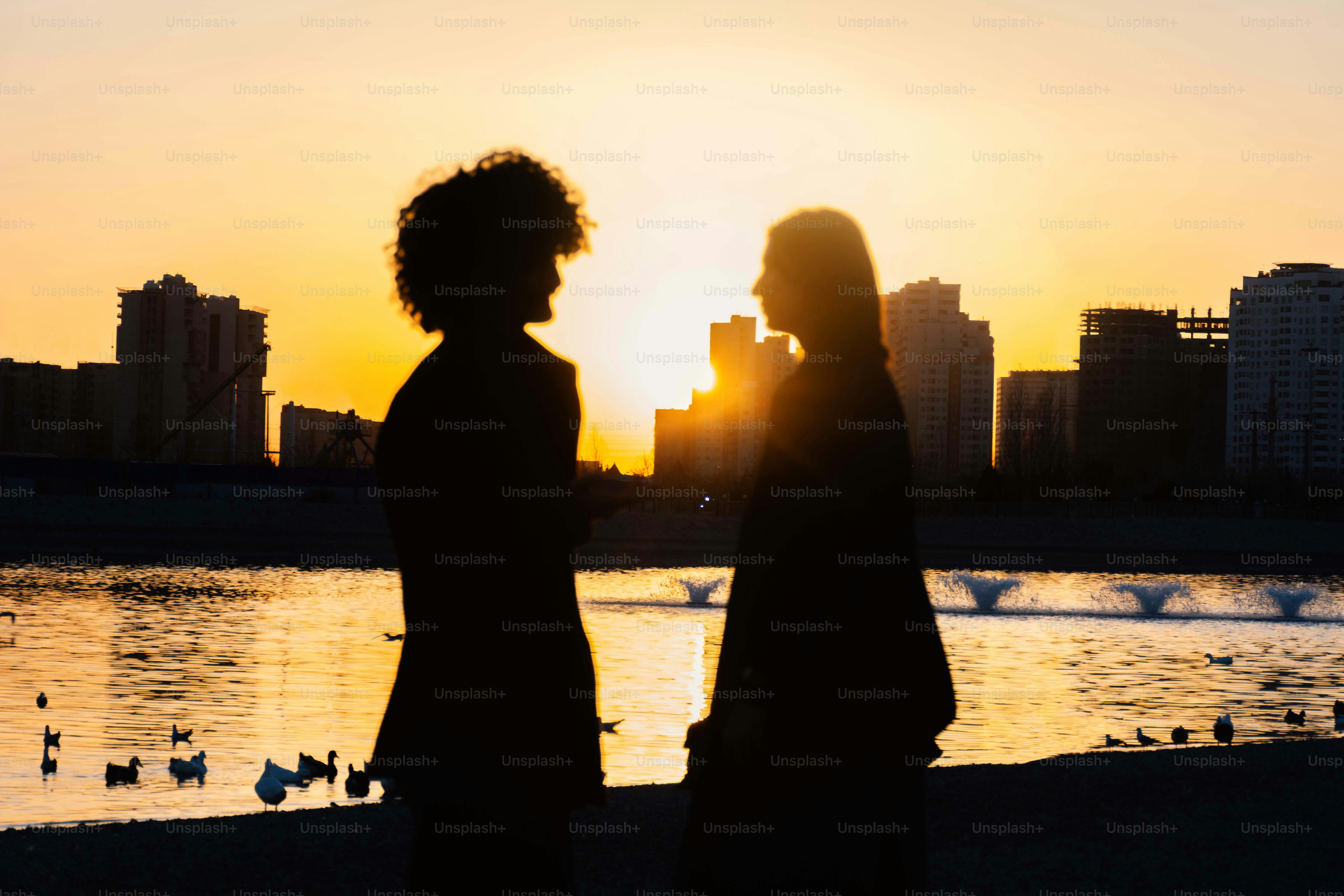 Dos personas hablando al atardecer con el skyline de la ciudad