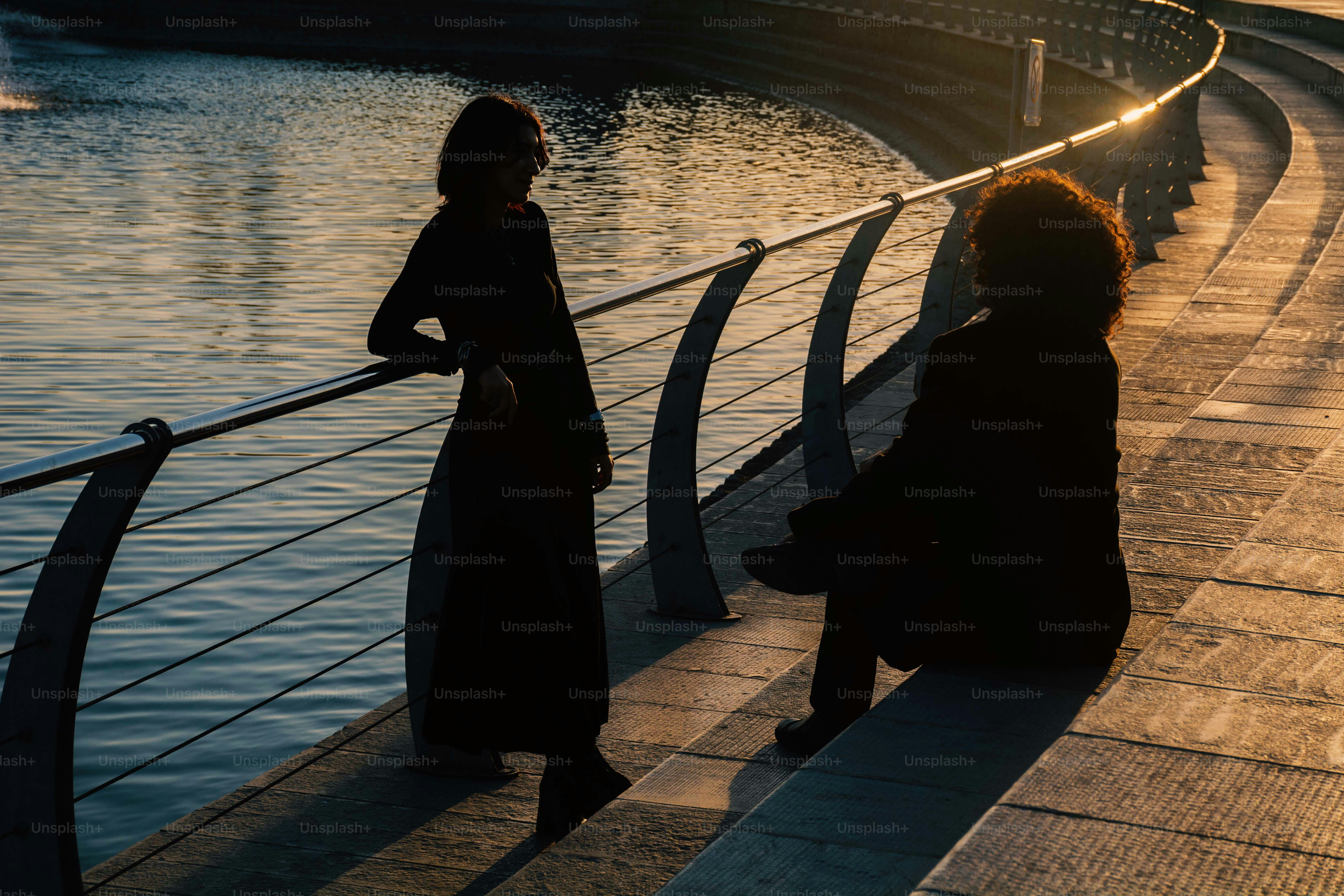 Dos personas recortadas por el sol poniente en un pasillo.