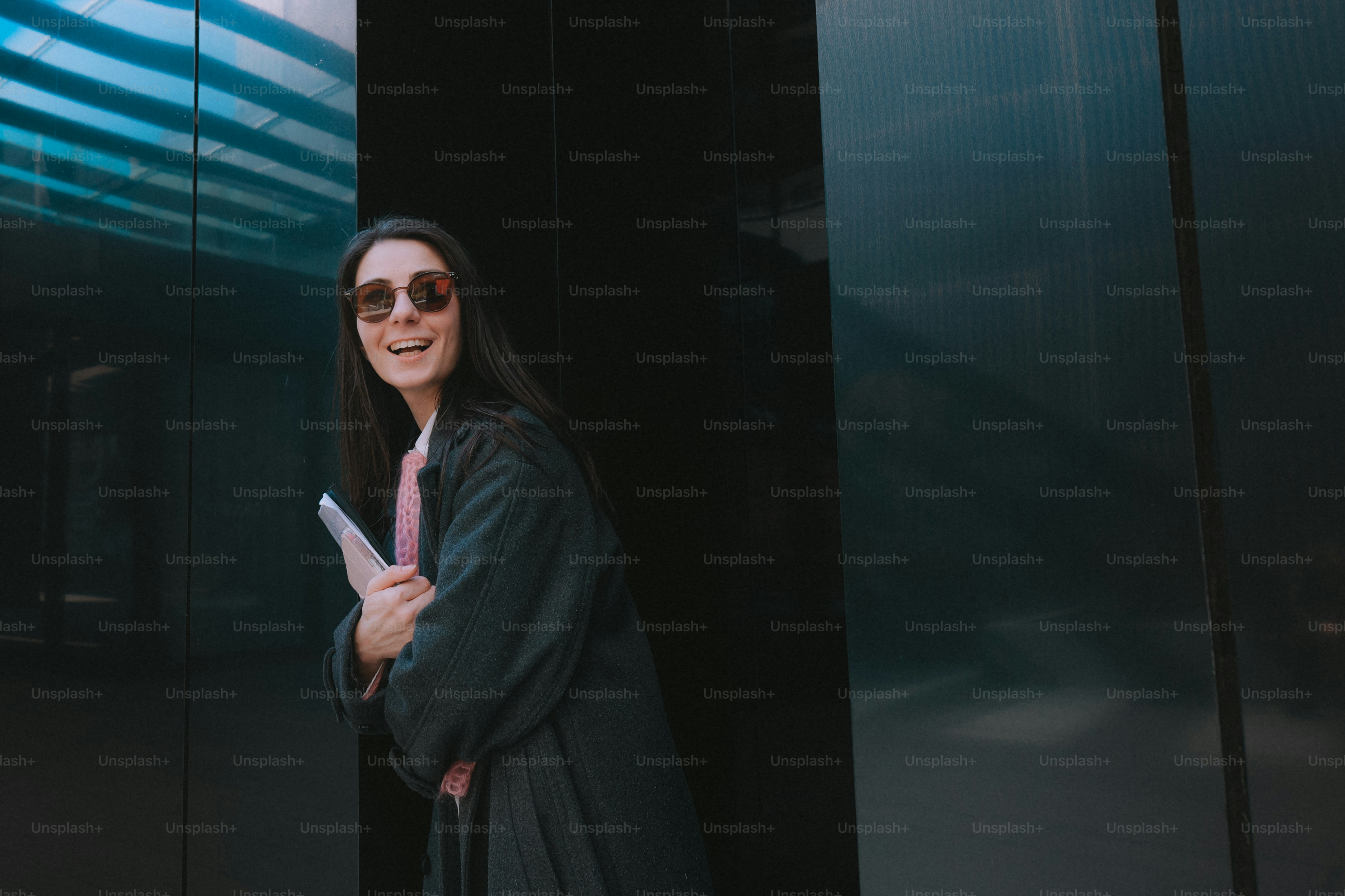 A woman in sunglasses holding a tablet outside.