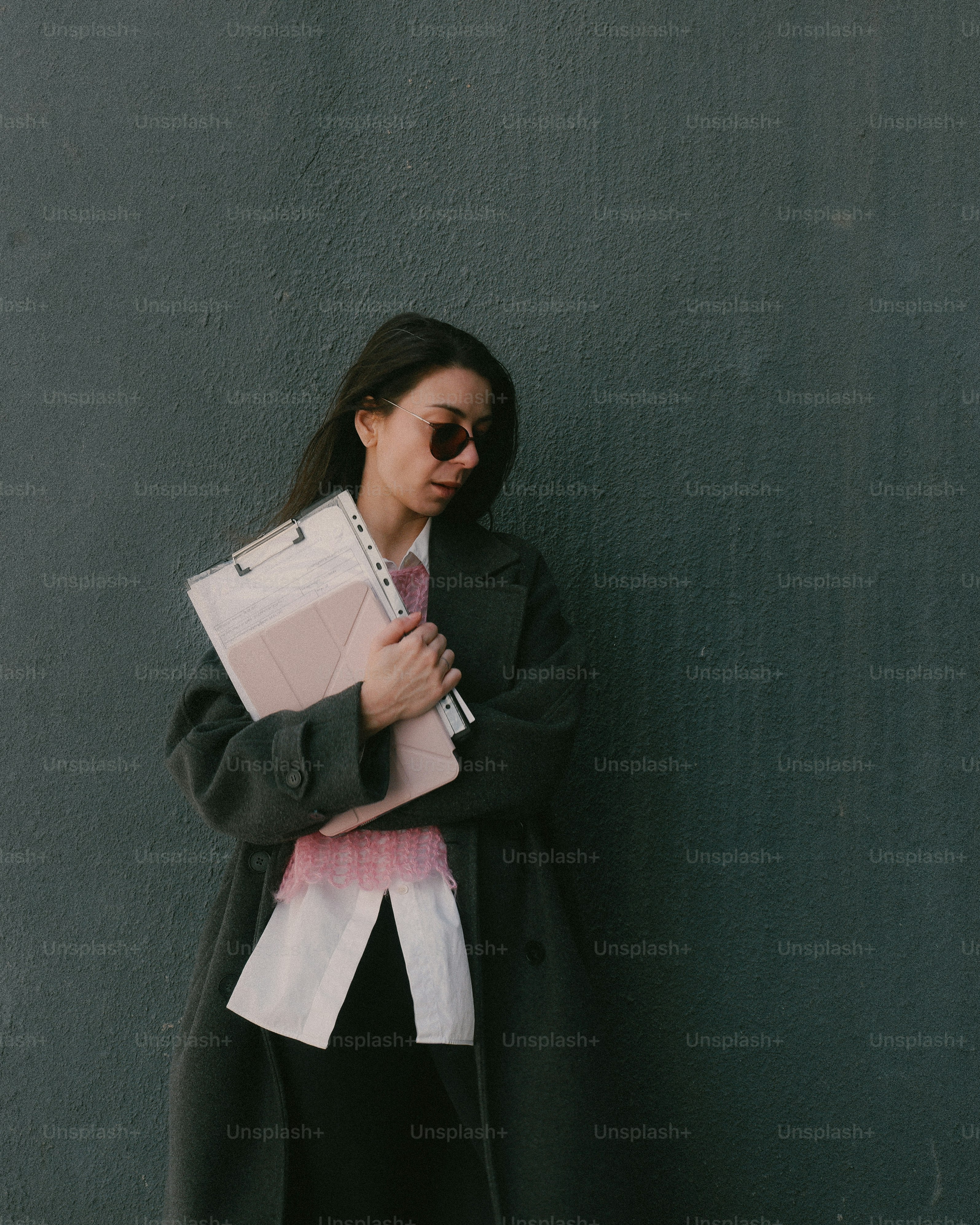 Woman holding a folder in front of a dark wall