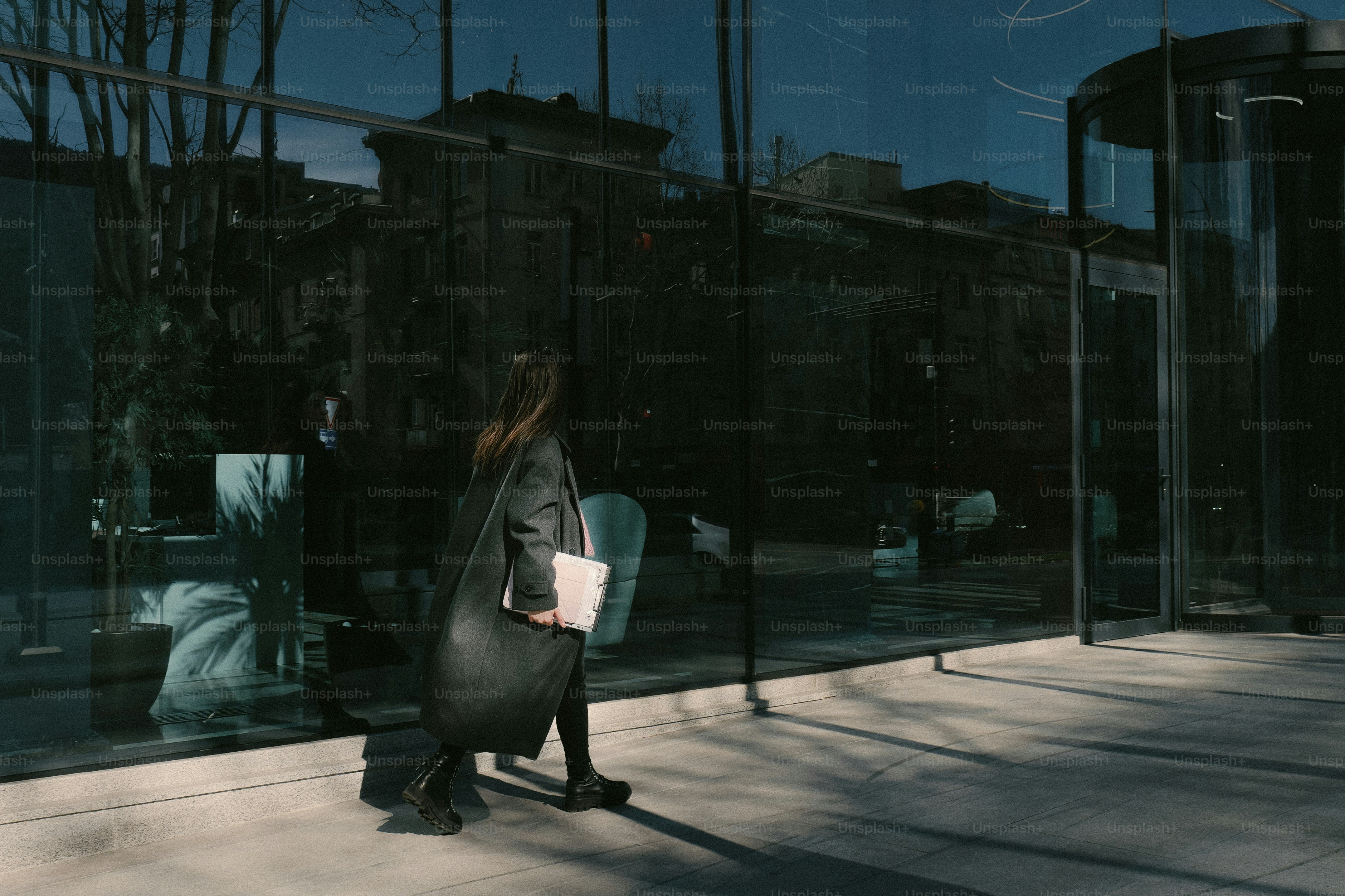 Woman walking by a reflective modern building.