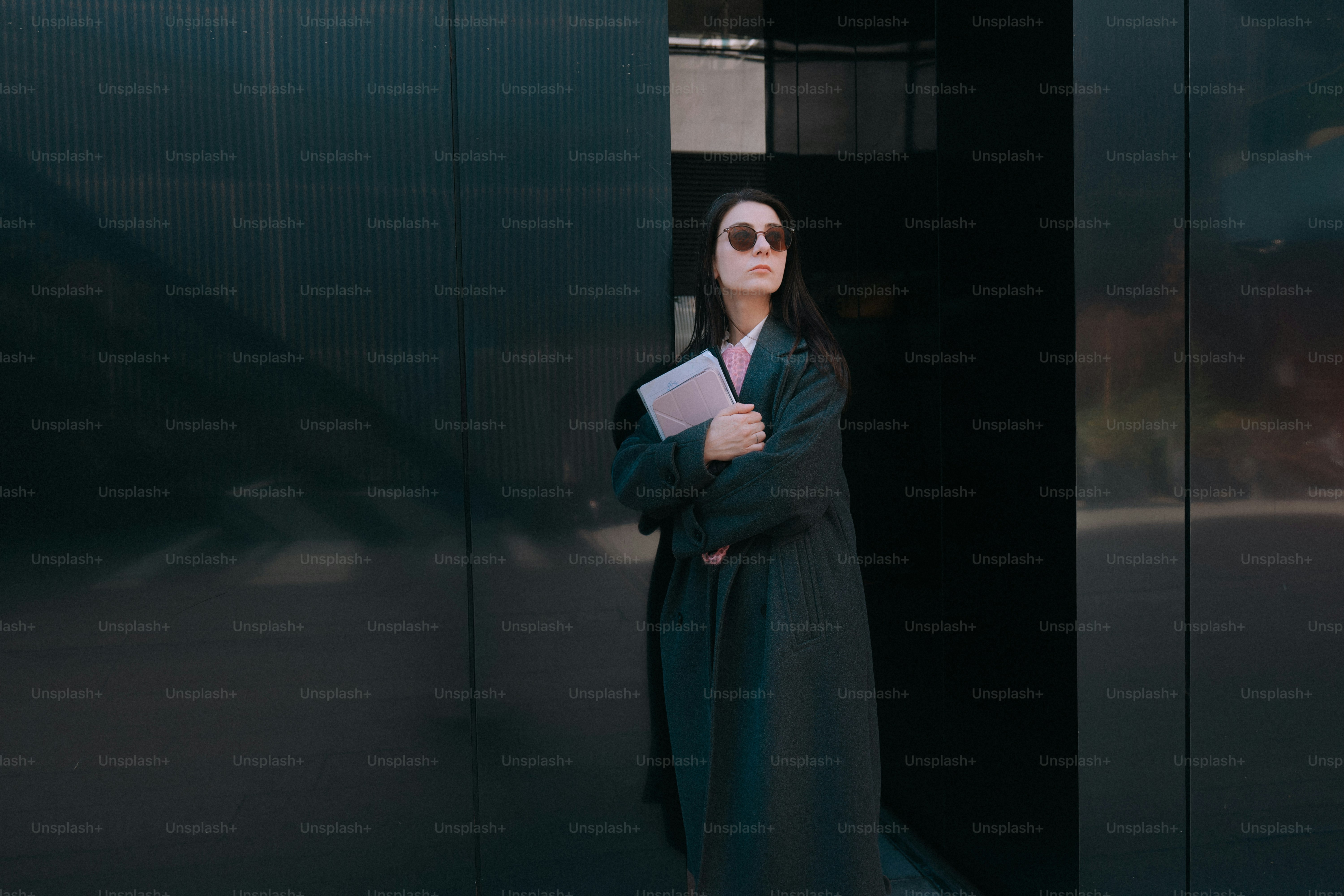 Woman in coat holding a tablet outside building