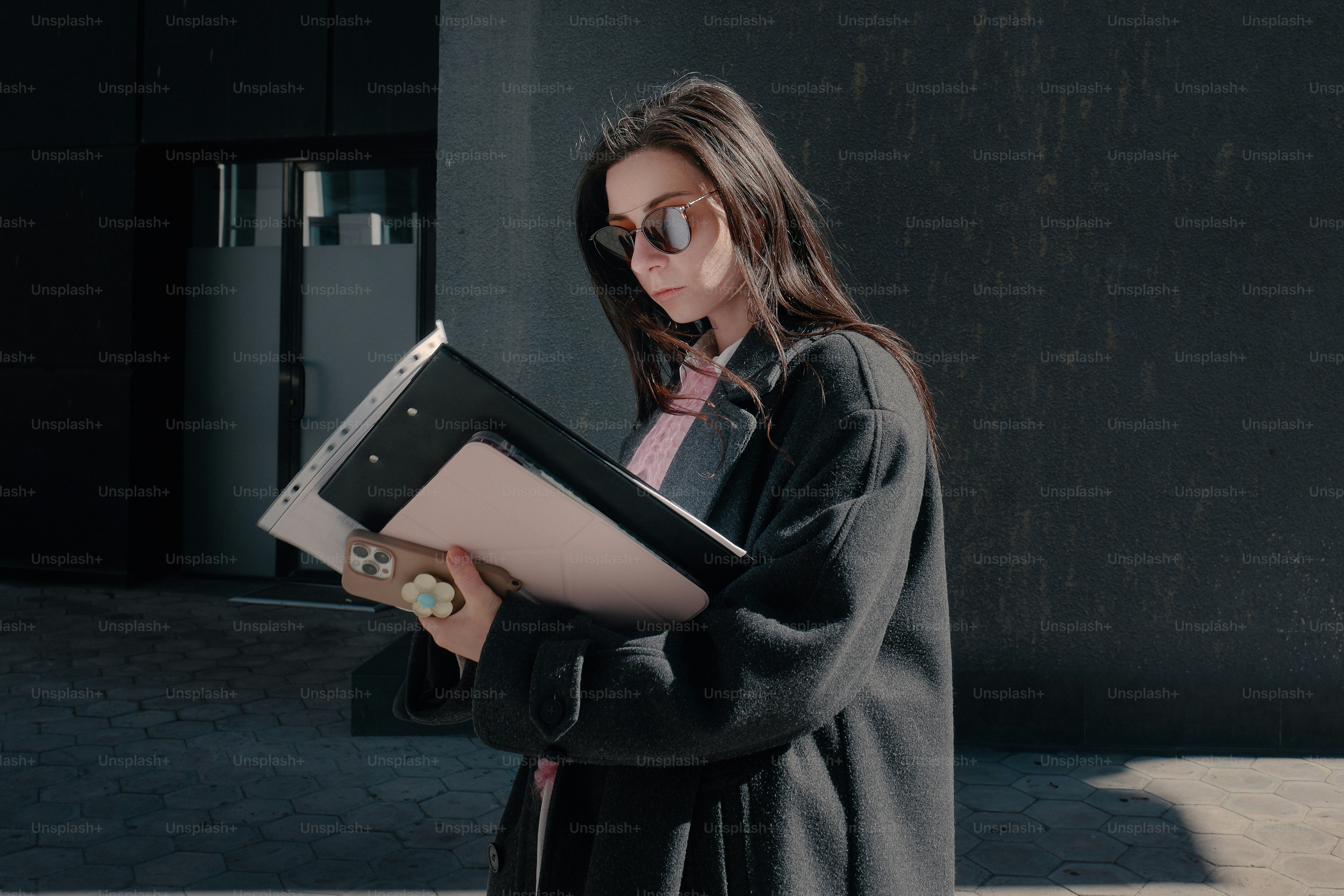 Woman in sunglasses holding folders and reading documents