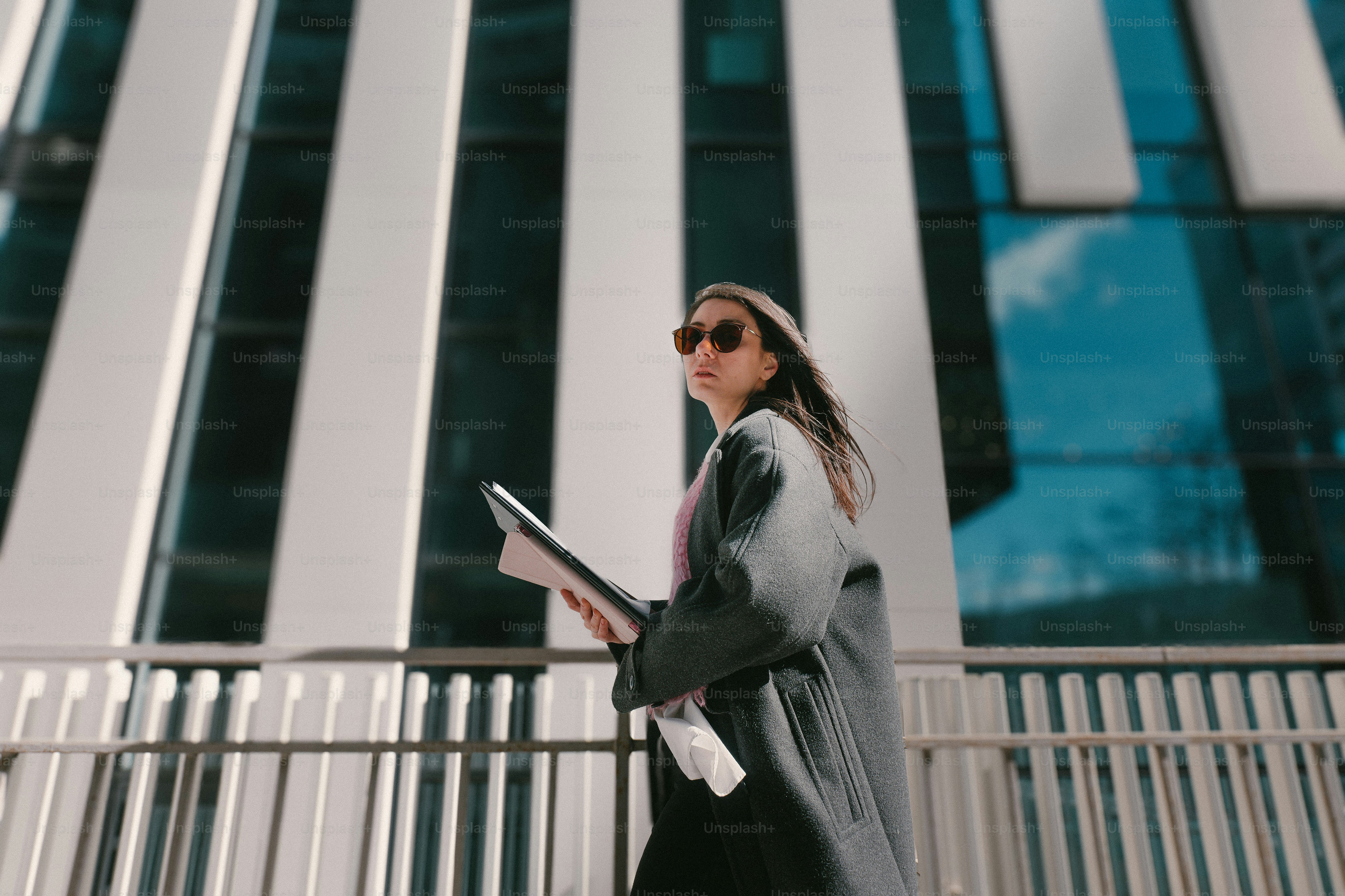 Woman walking with documents near modern building