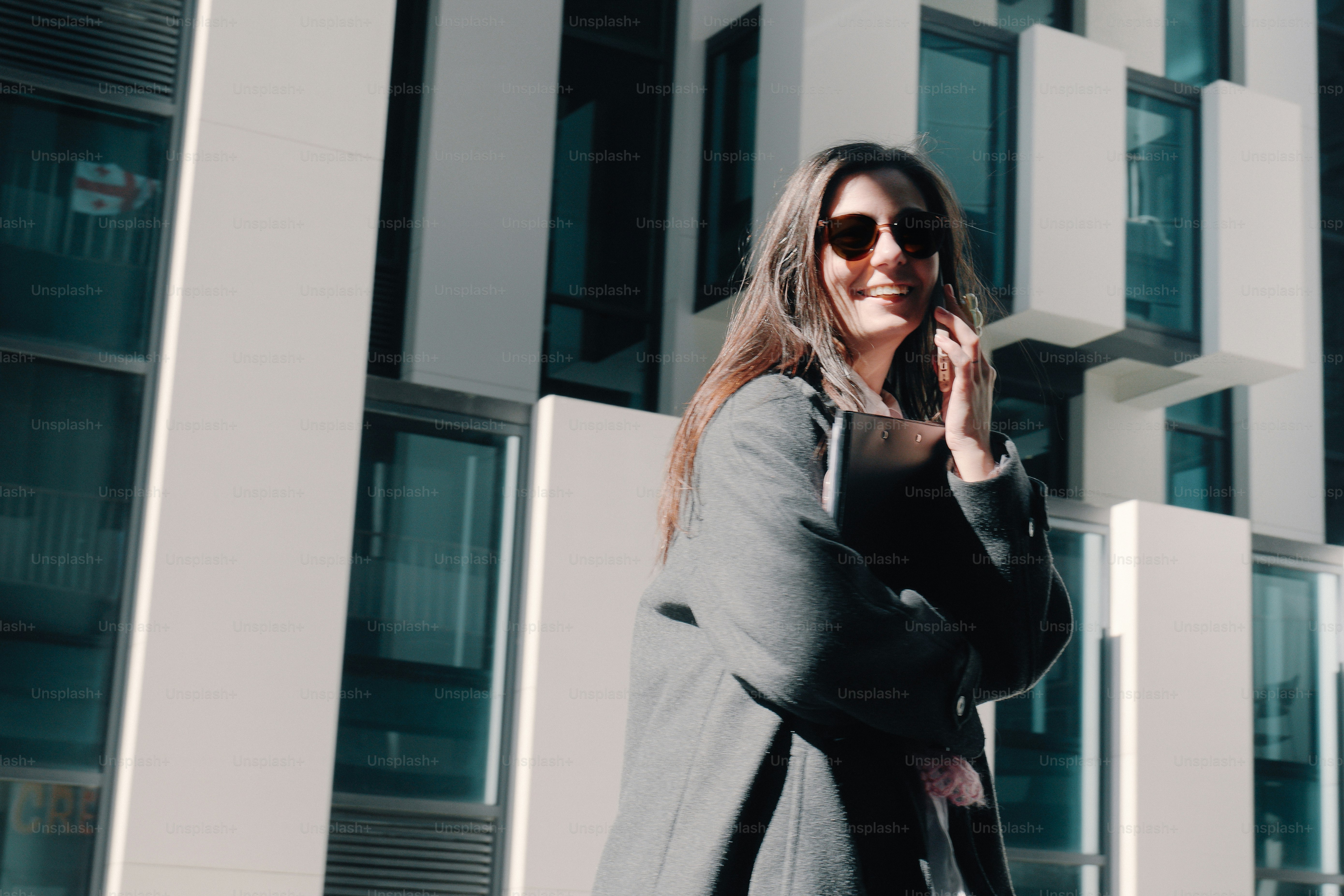 A woman in a coat and sunglasses smiles