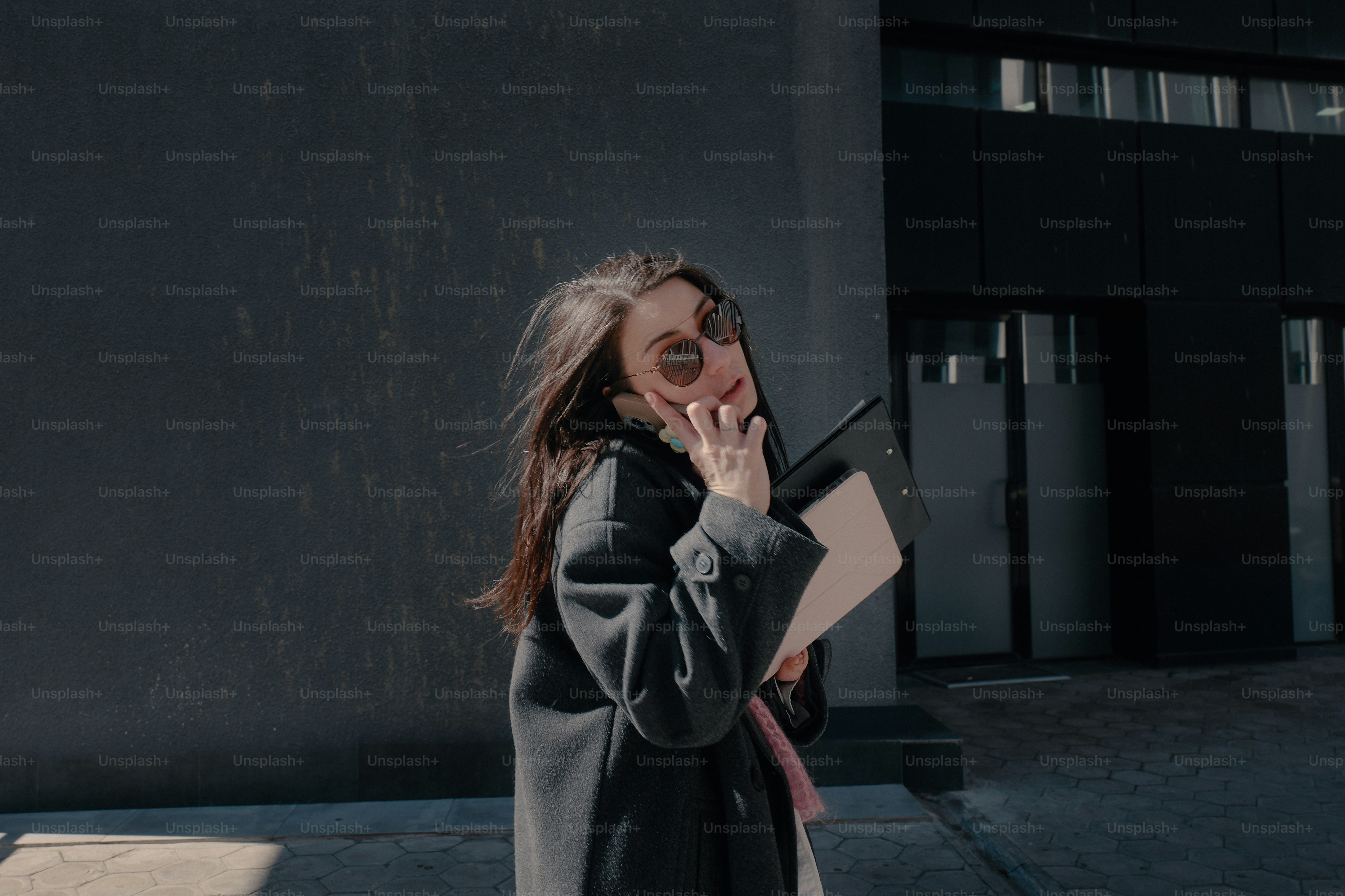 A woman walks with a laptop and documents.