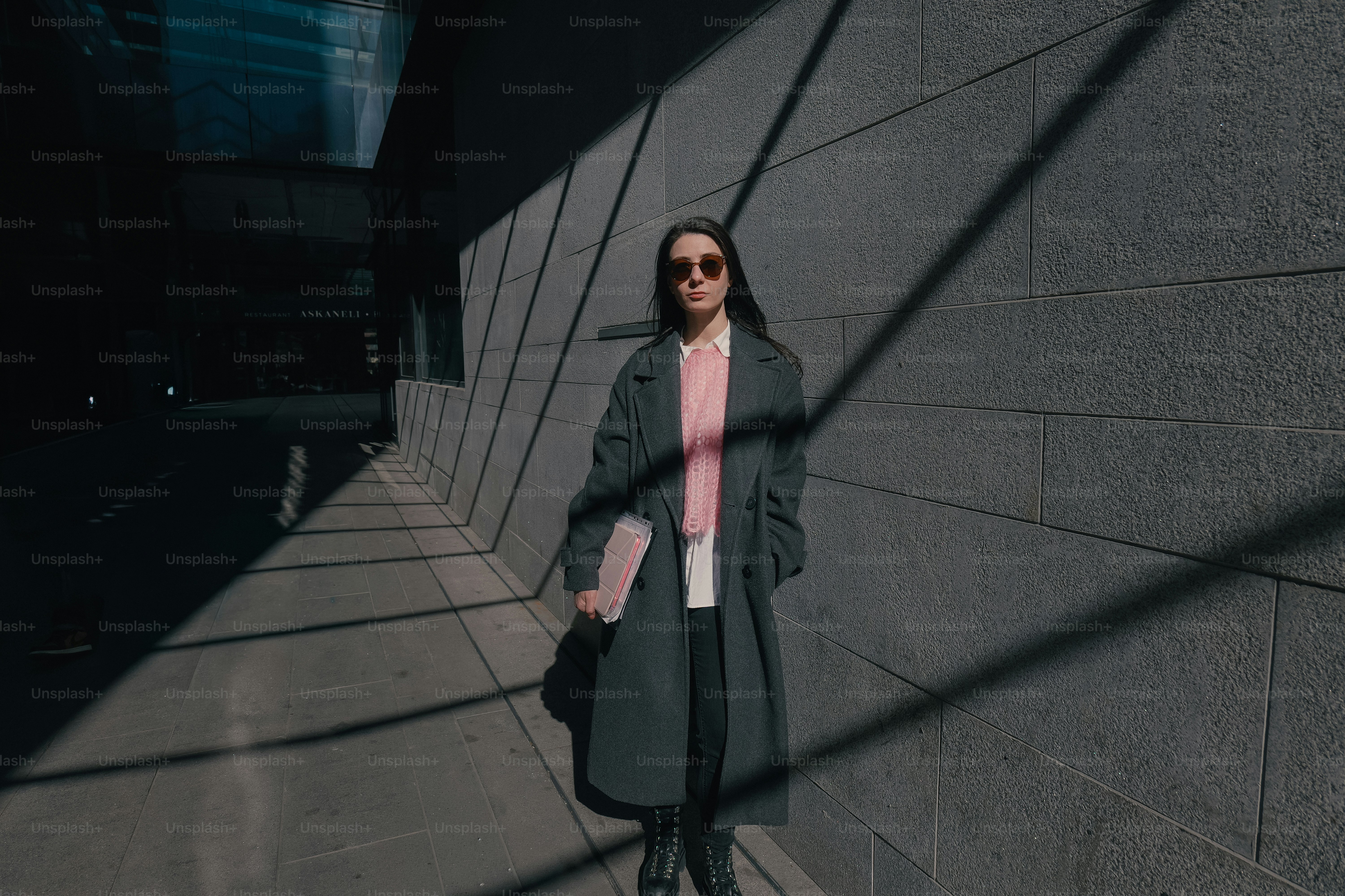 Woman in coat walks in sunlight and shadow