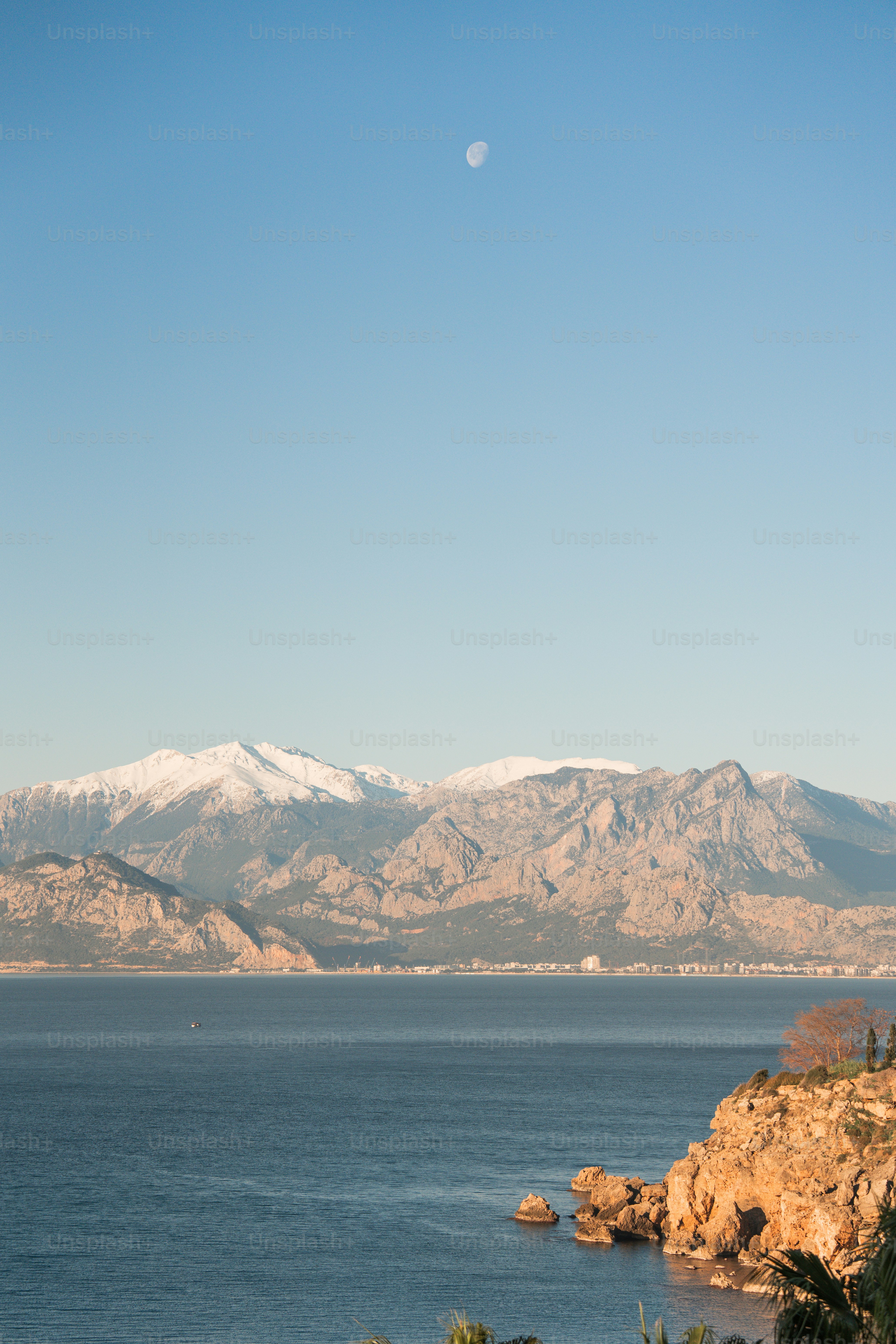 Snow-capped mountains rise above a calm sea.