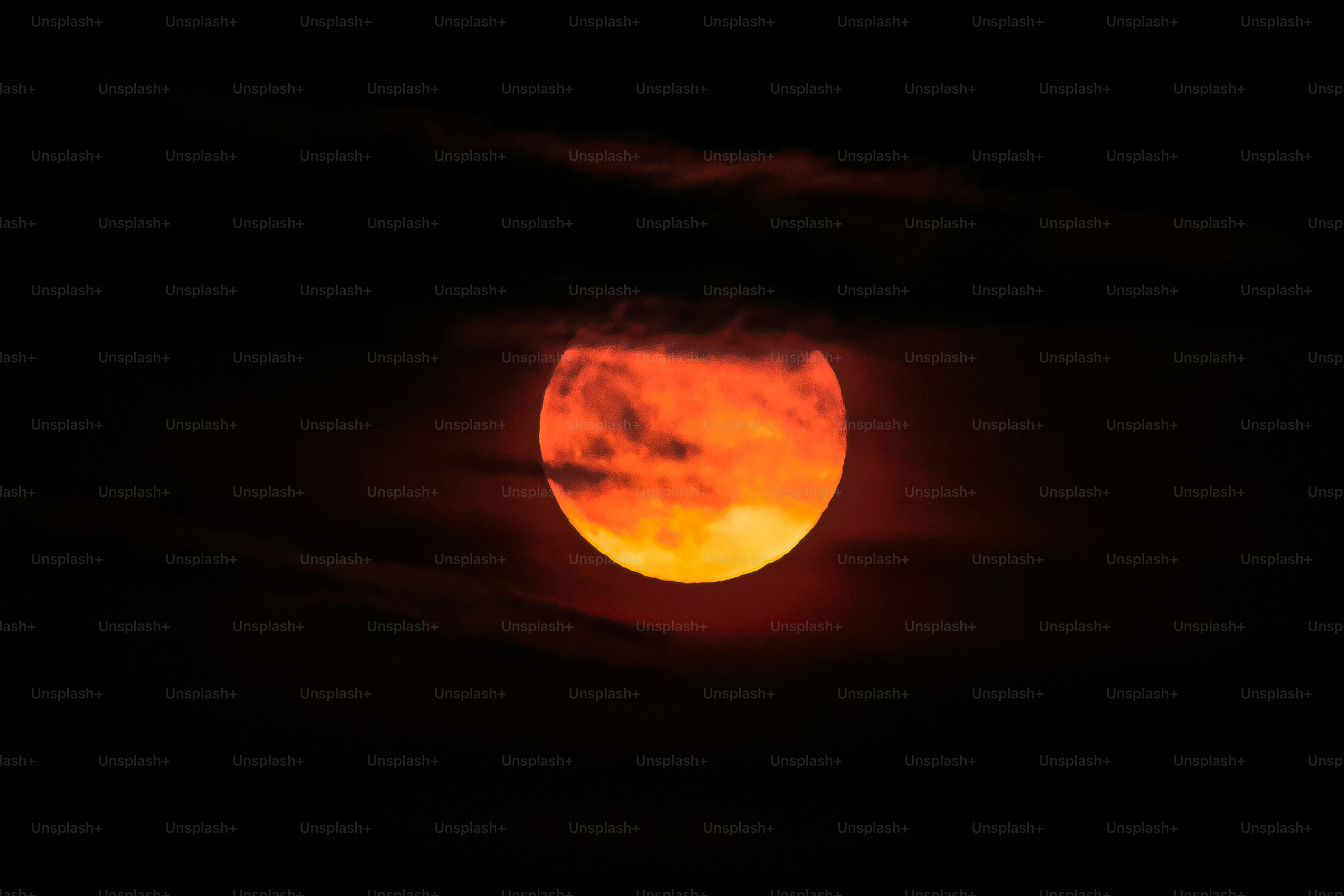 A large, glowing orange moon partially obscured by dark clouds.