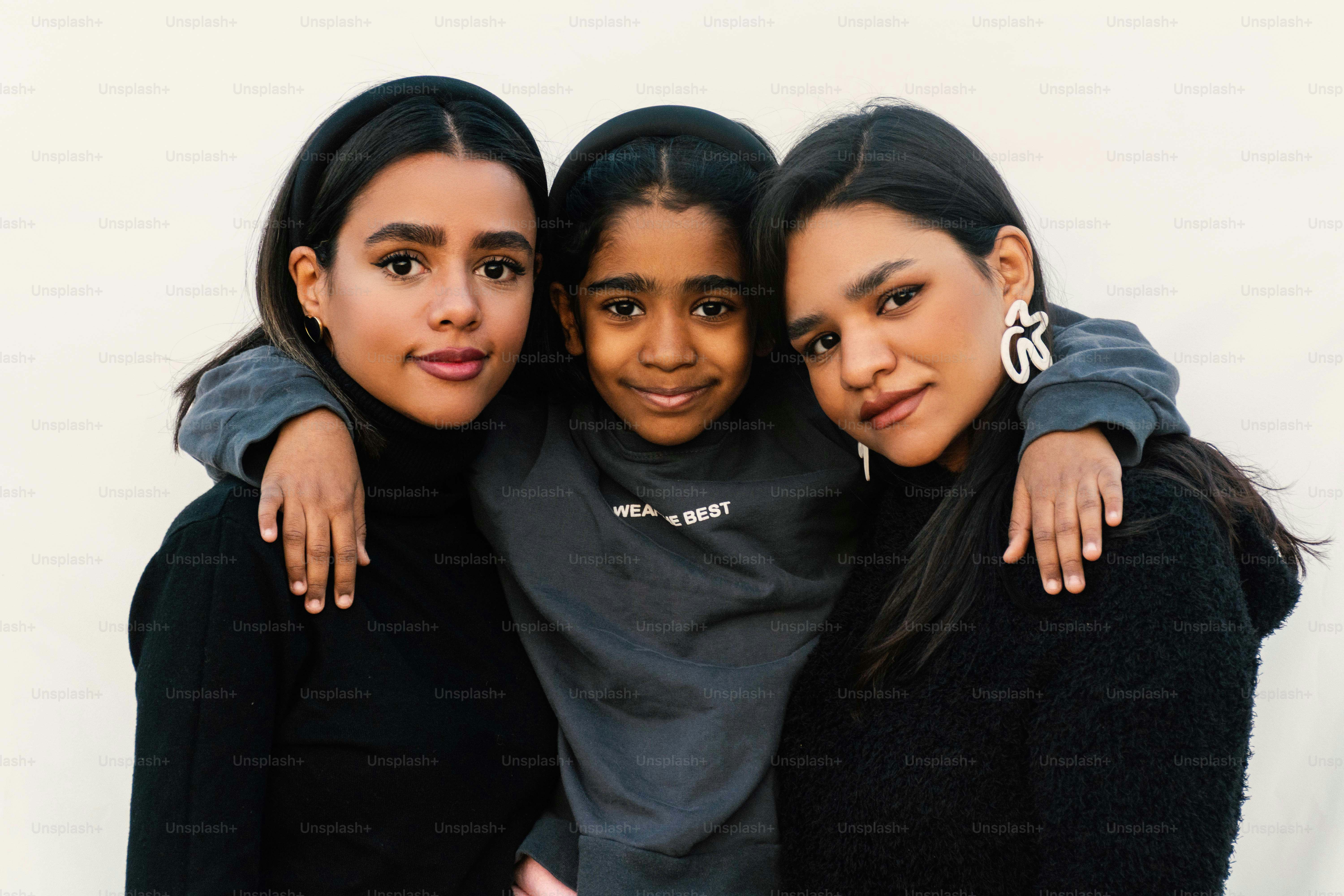 Tres jóvenes posando juntas en un fondo neutral.