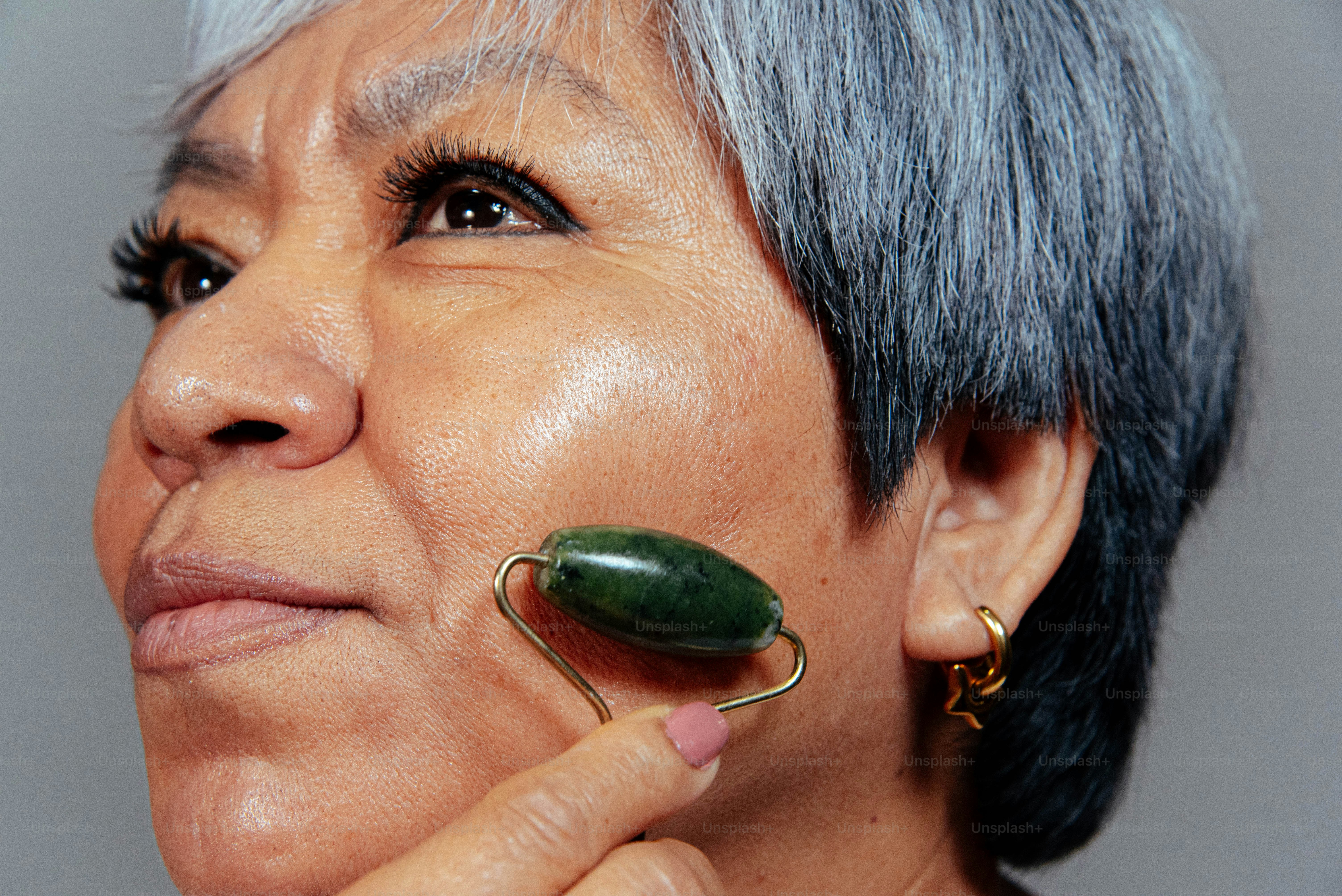 노부인이 얼굴에 옥 롤러를 사용함