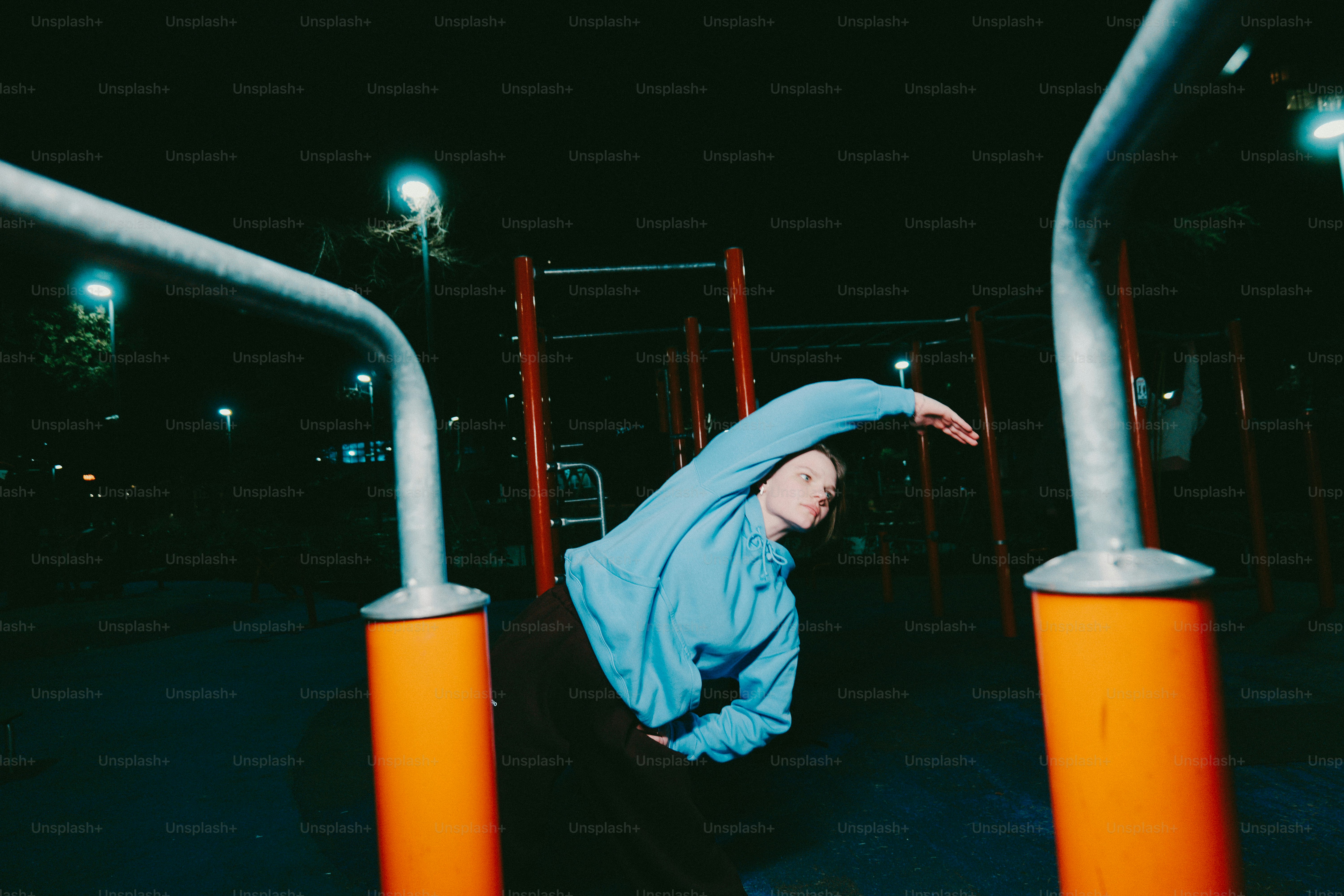 Person stretching on outdoor gym equipment at night.