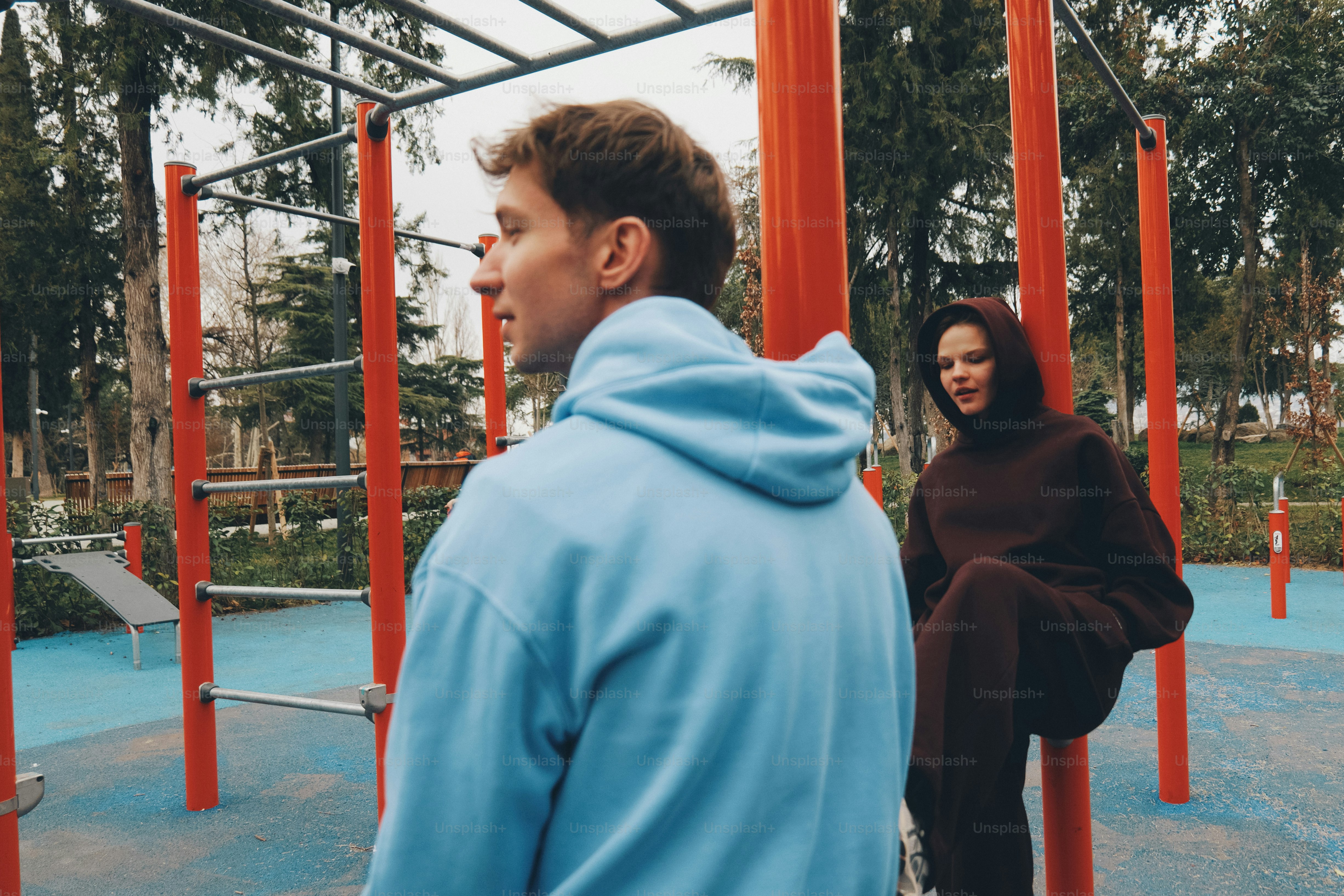 Two people in hoodies at an outdoor gym
