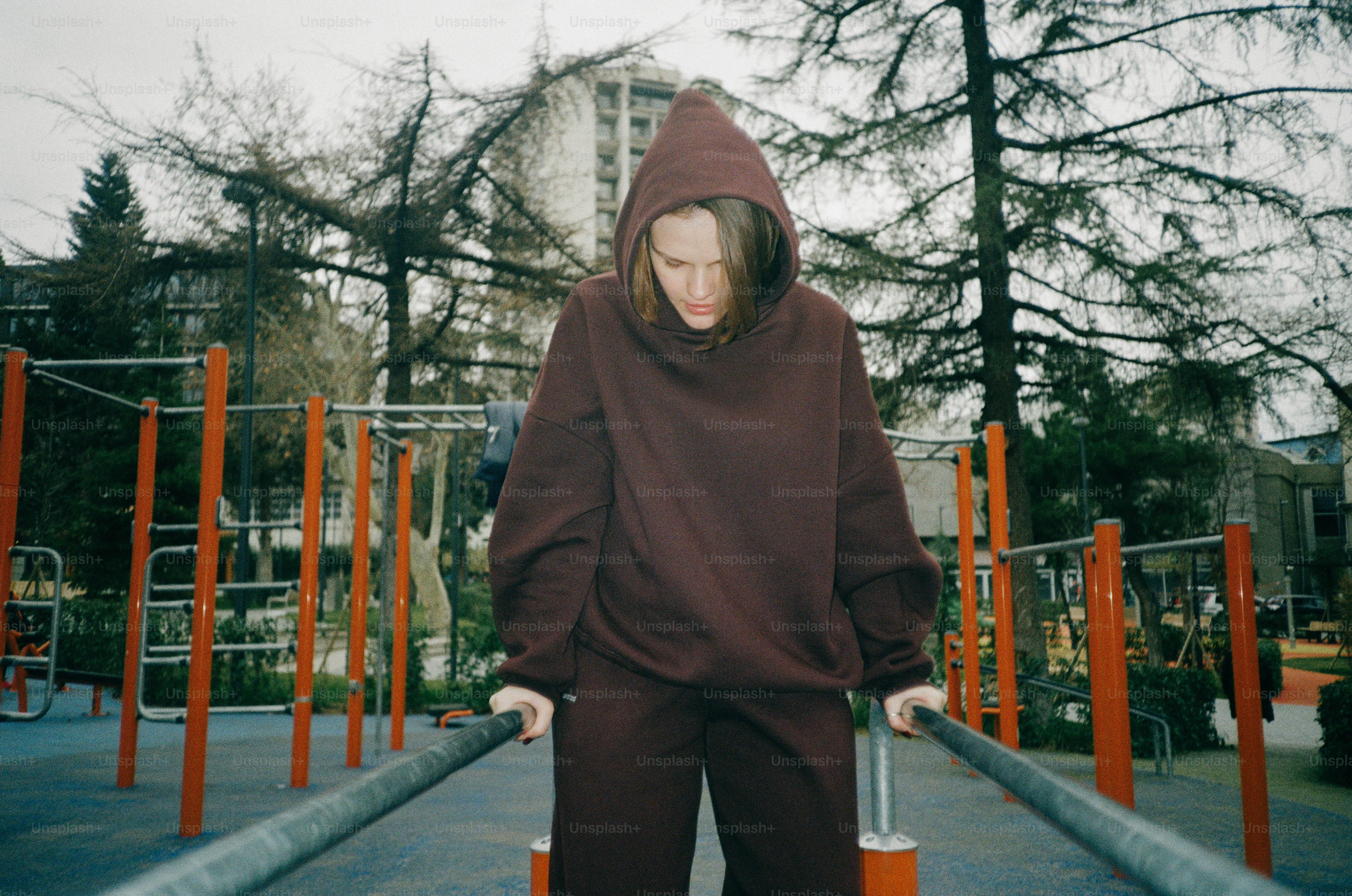Woman in a hoodie on parallel bars outdoors