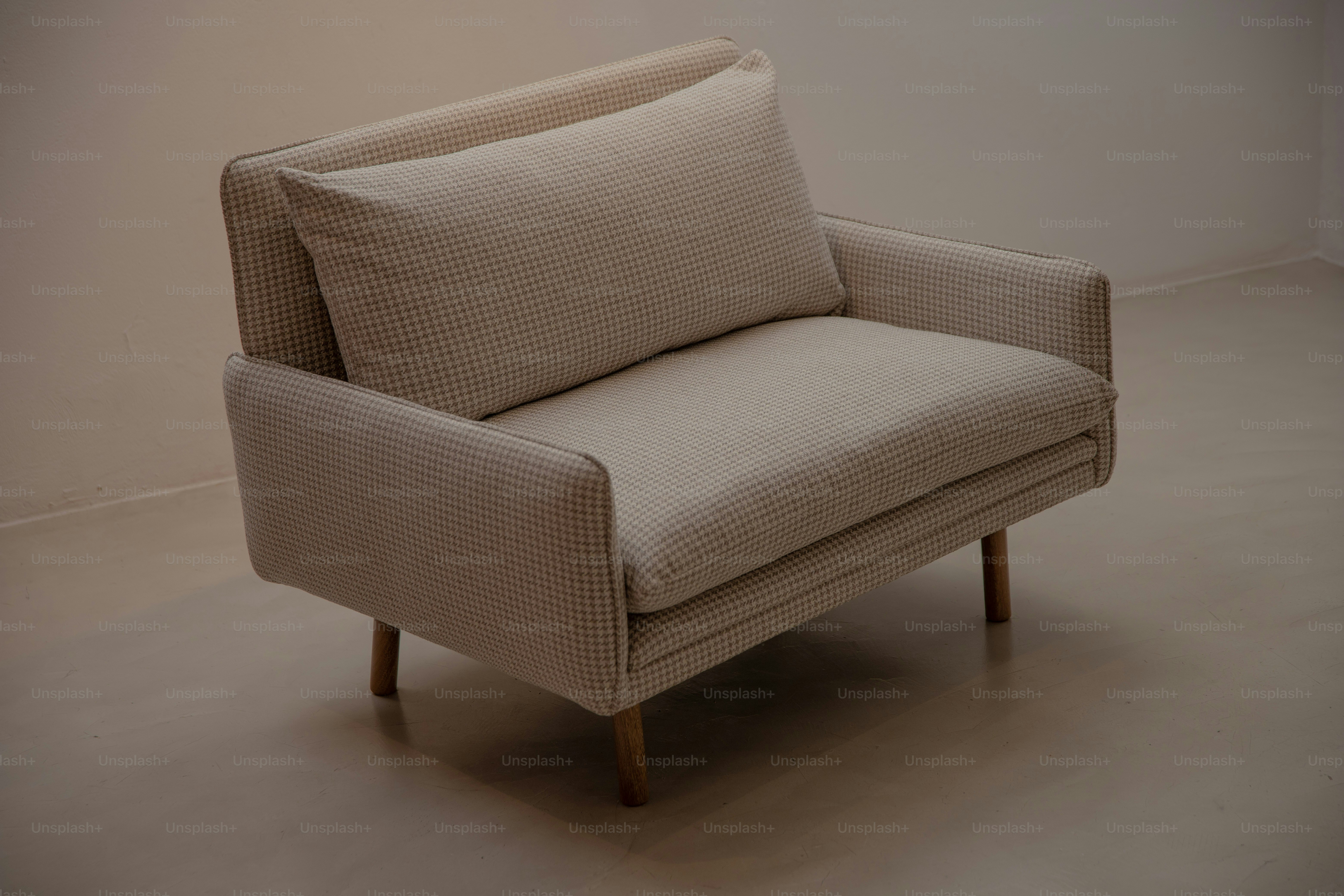 A modern beige armchair with a single cushion.