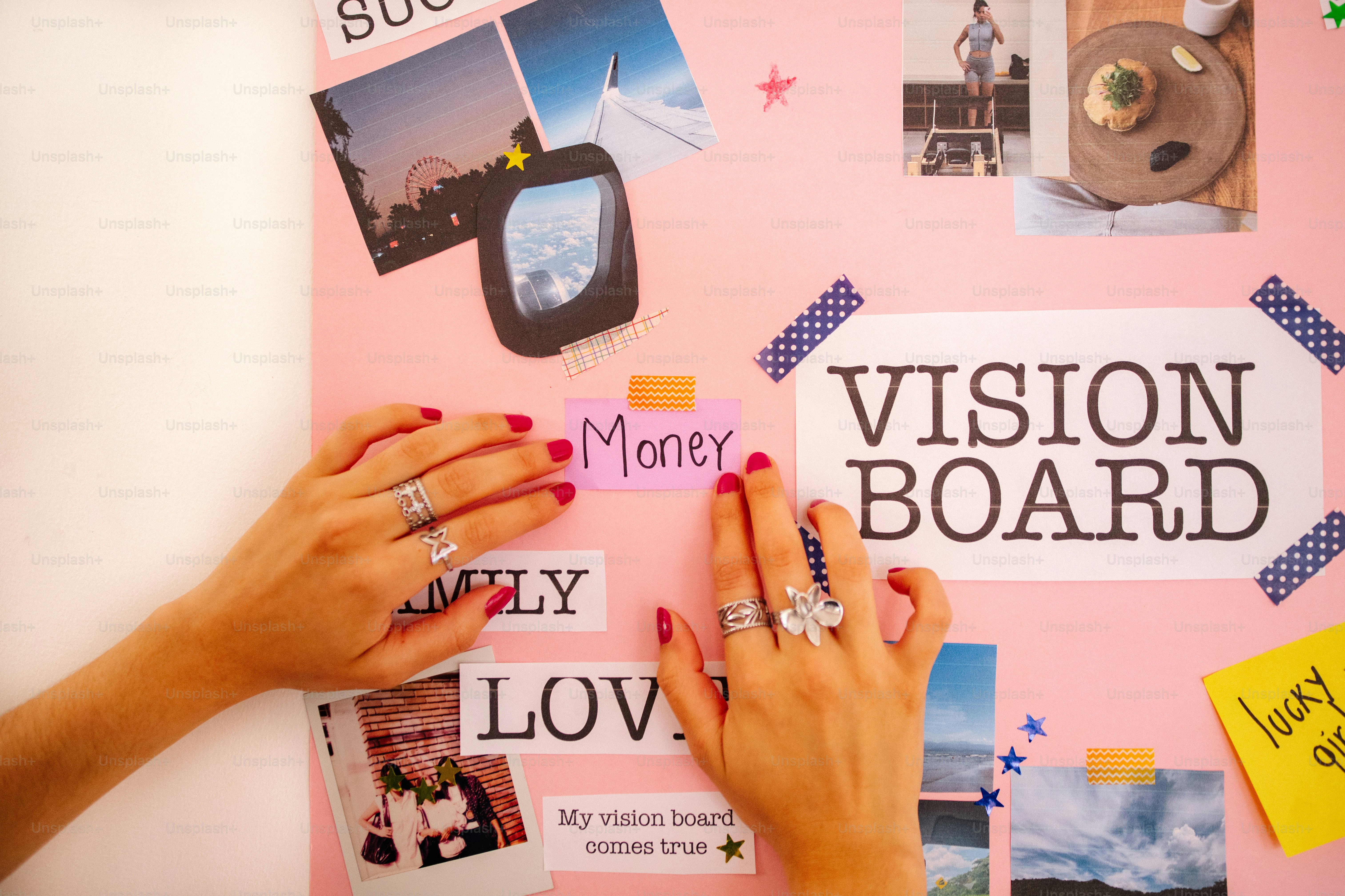 Hands arranging items on a pink vision board.