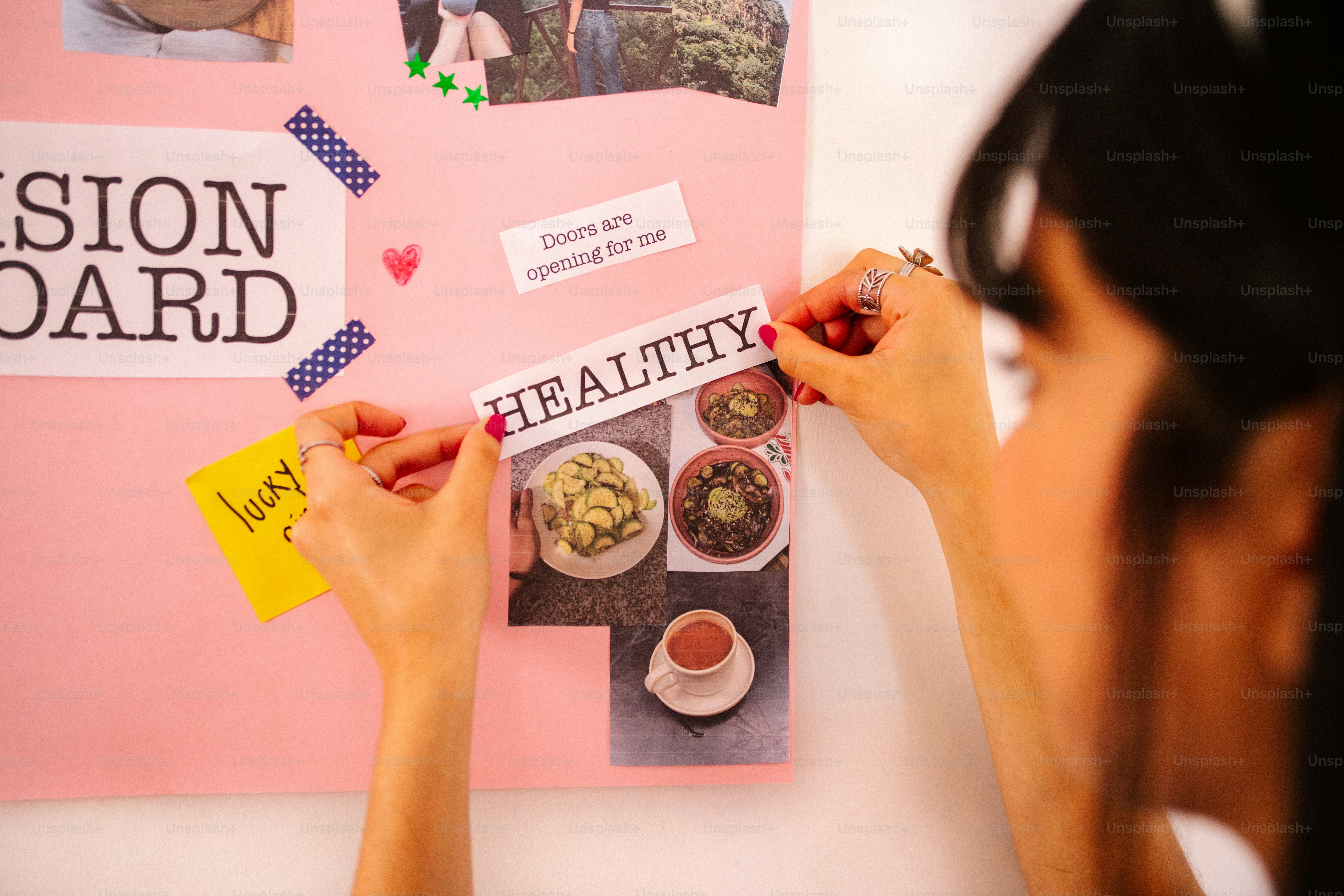 Woman adding "healthy" to a vision board.