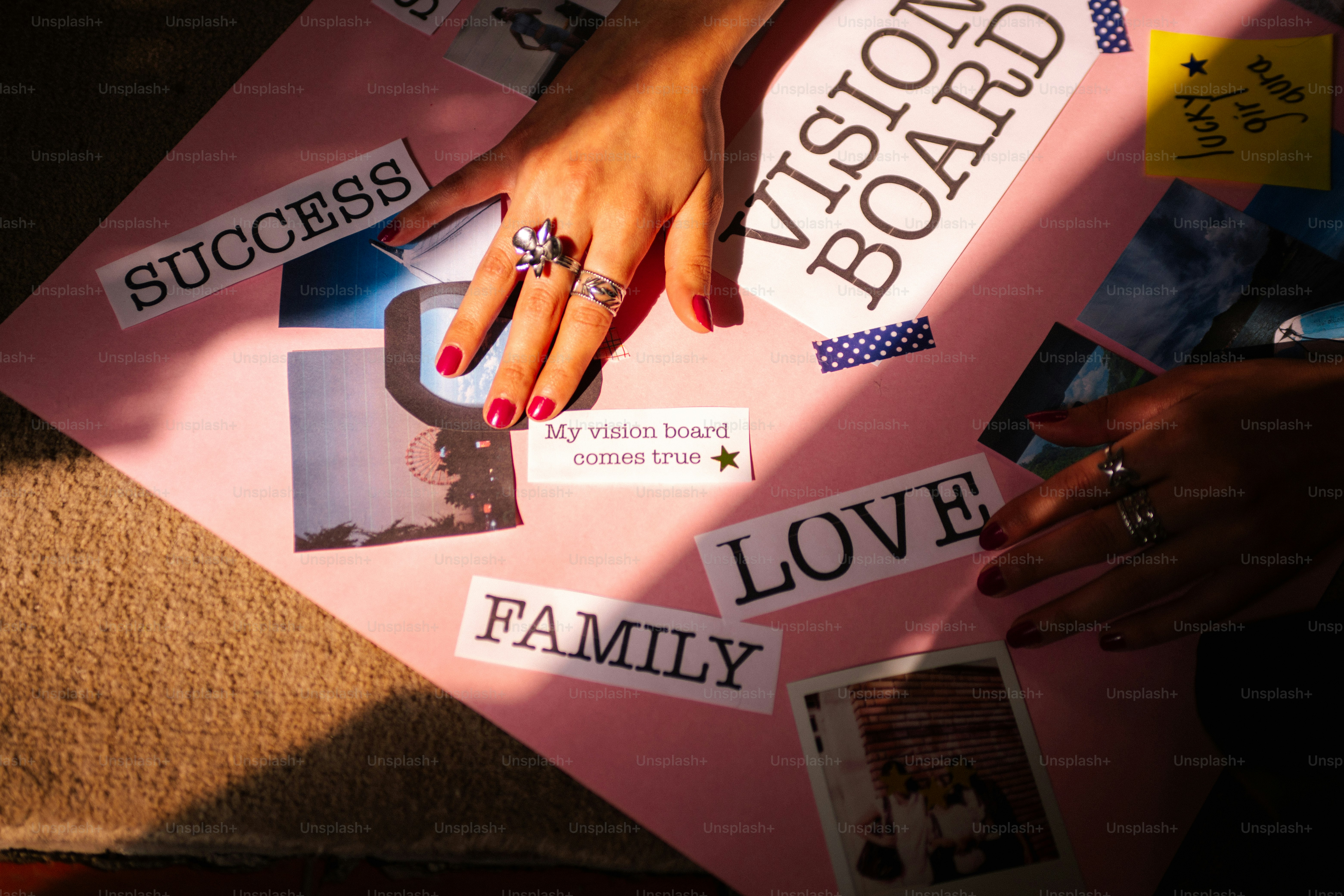Hands arranging words and pictures on a vision board.