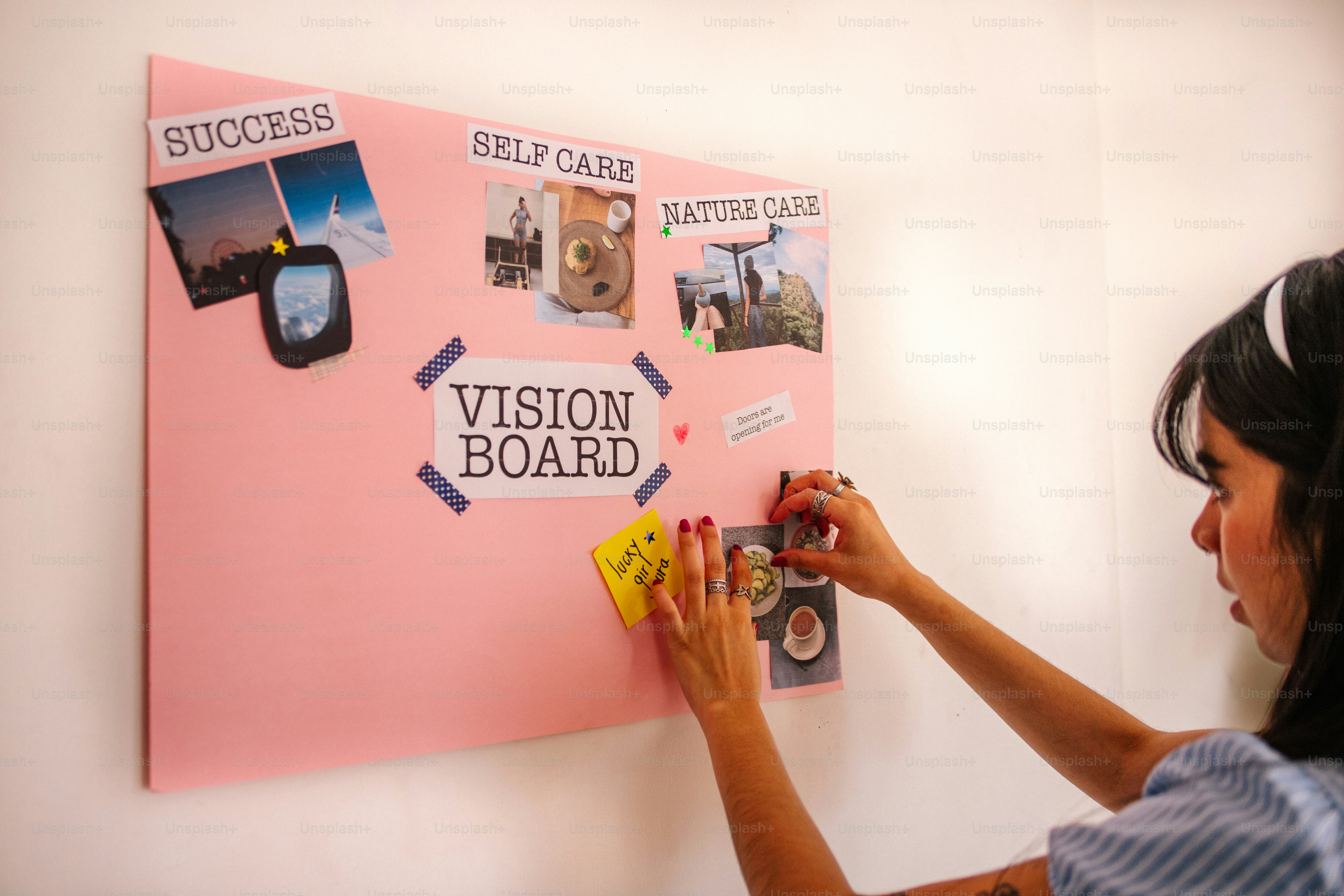 Woman adding pictures to a pink vision board.