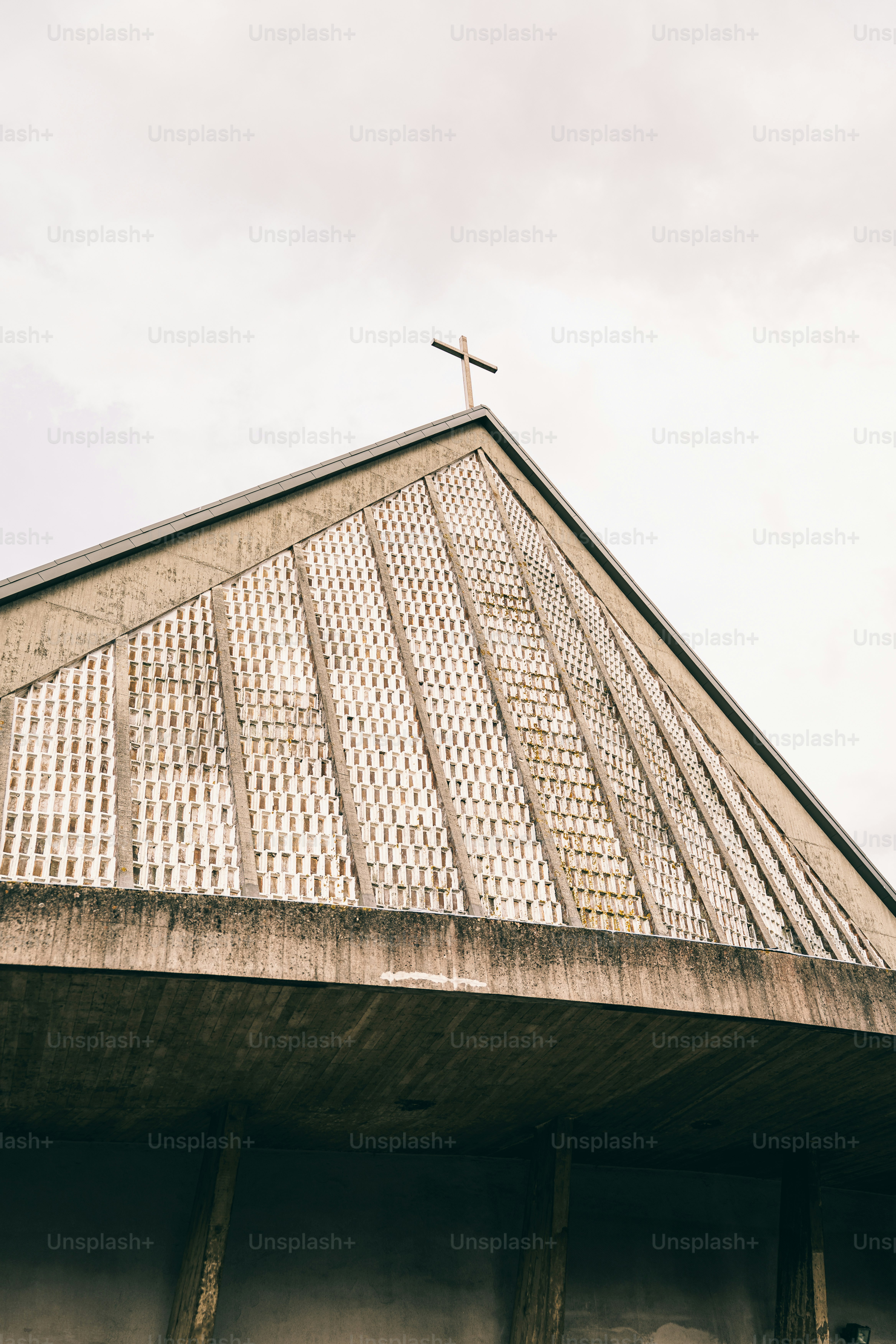 Modern church roof with a cross against a cloudy sky