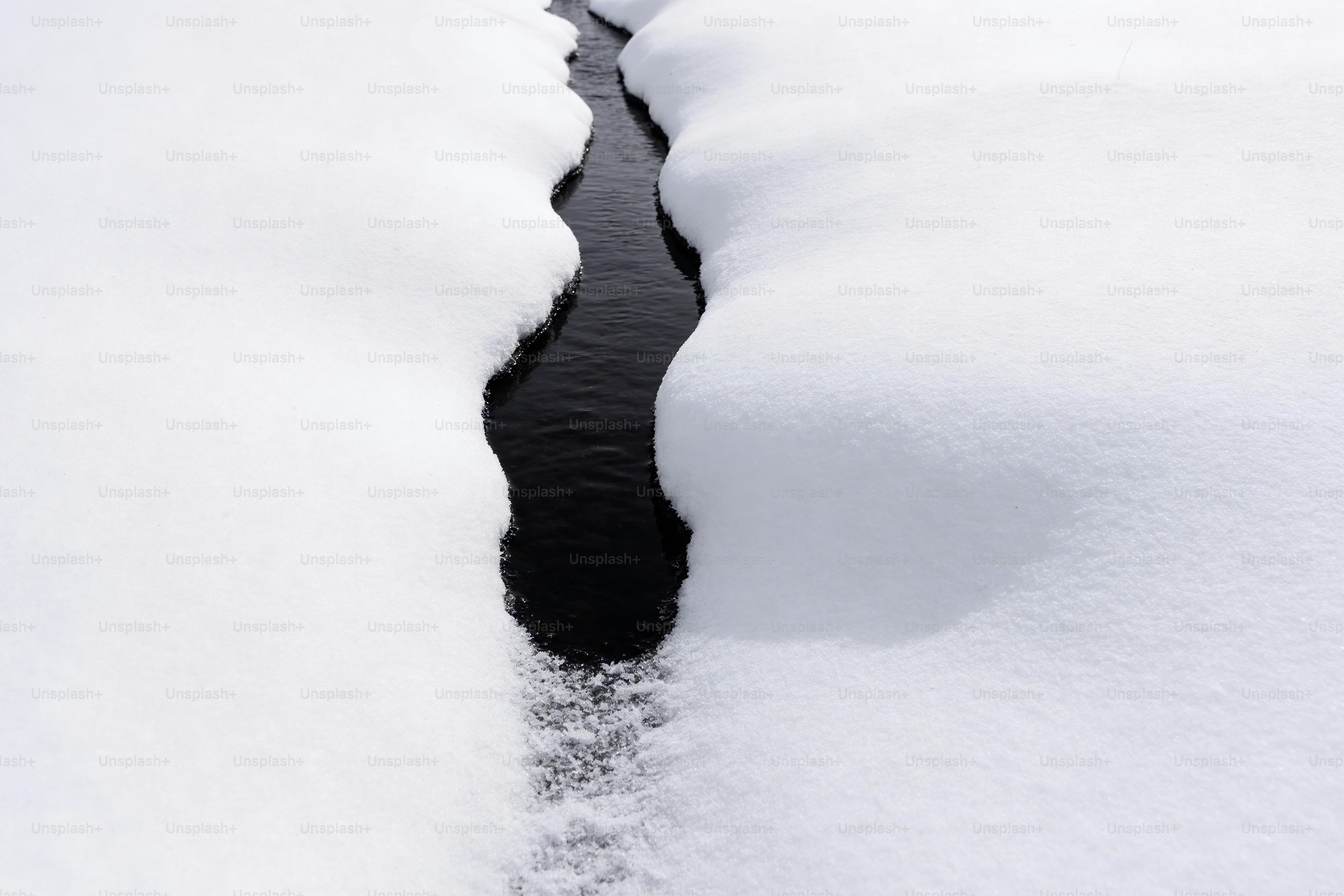 Un ruisseau étroit traverse un paysage enneigé.