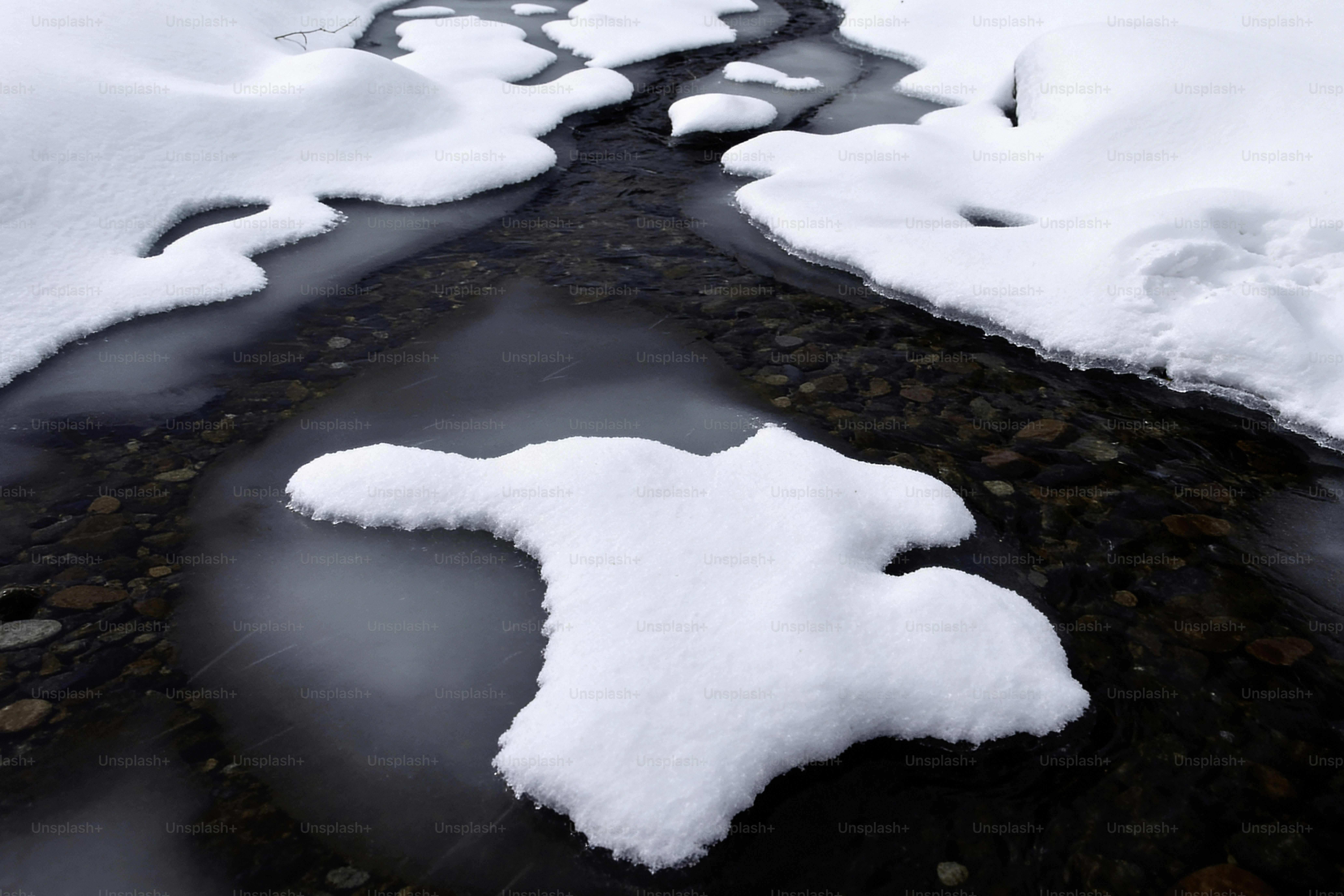 Neige fondante révélant un lit rocheux de ruisseau